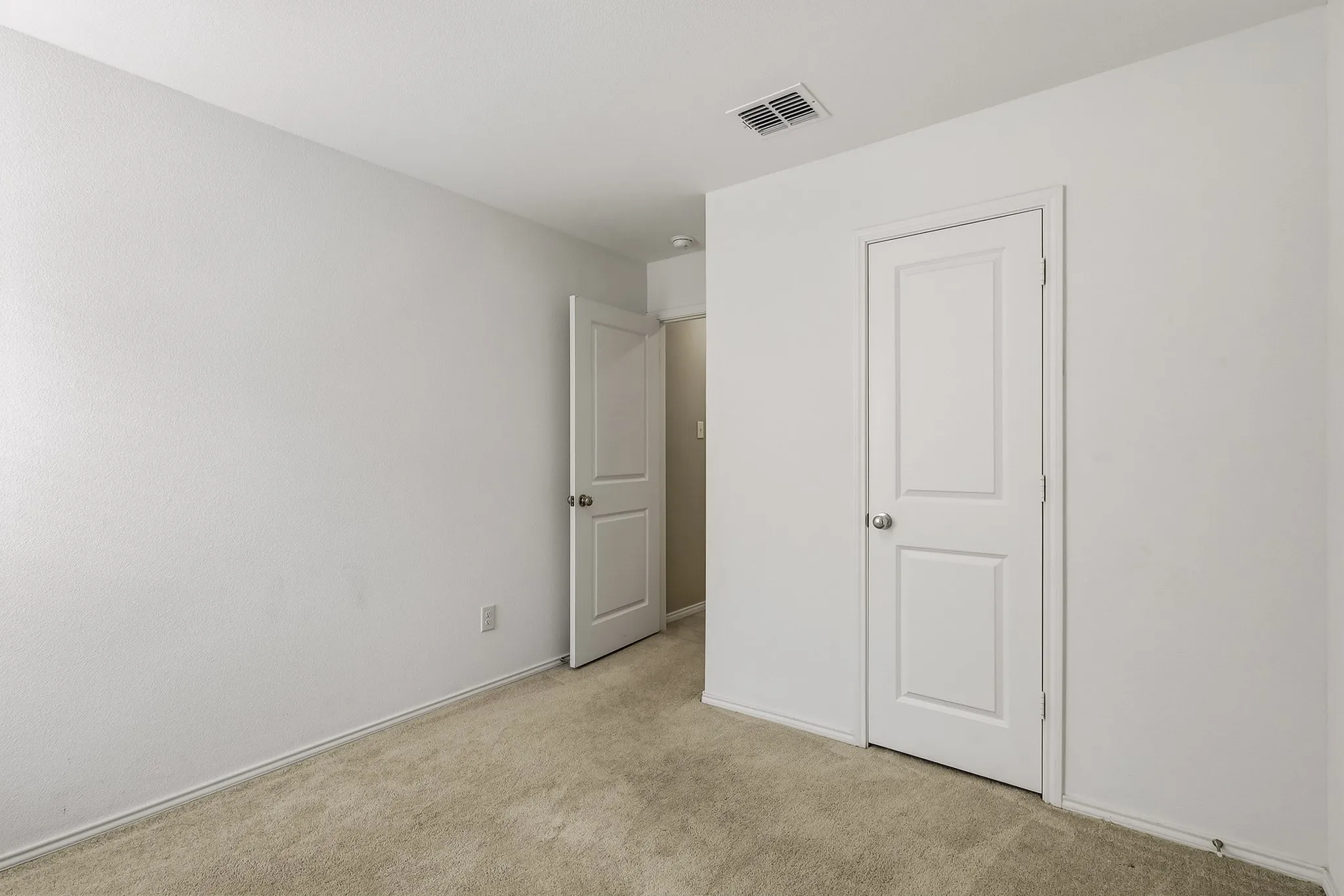 Neutral wall paint, carpet flooring, and white two-panel doors