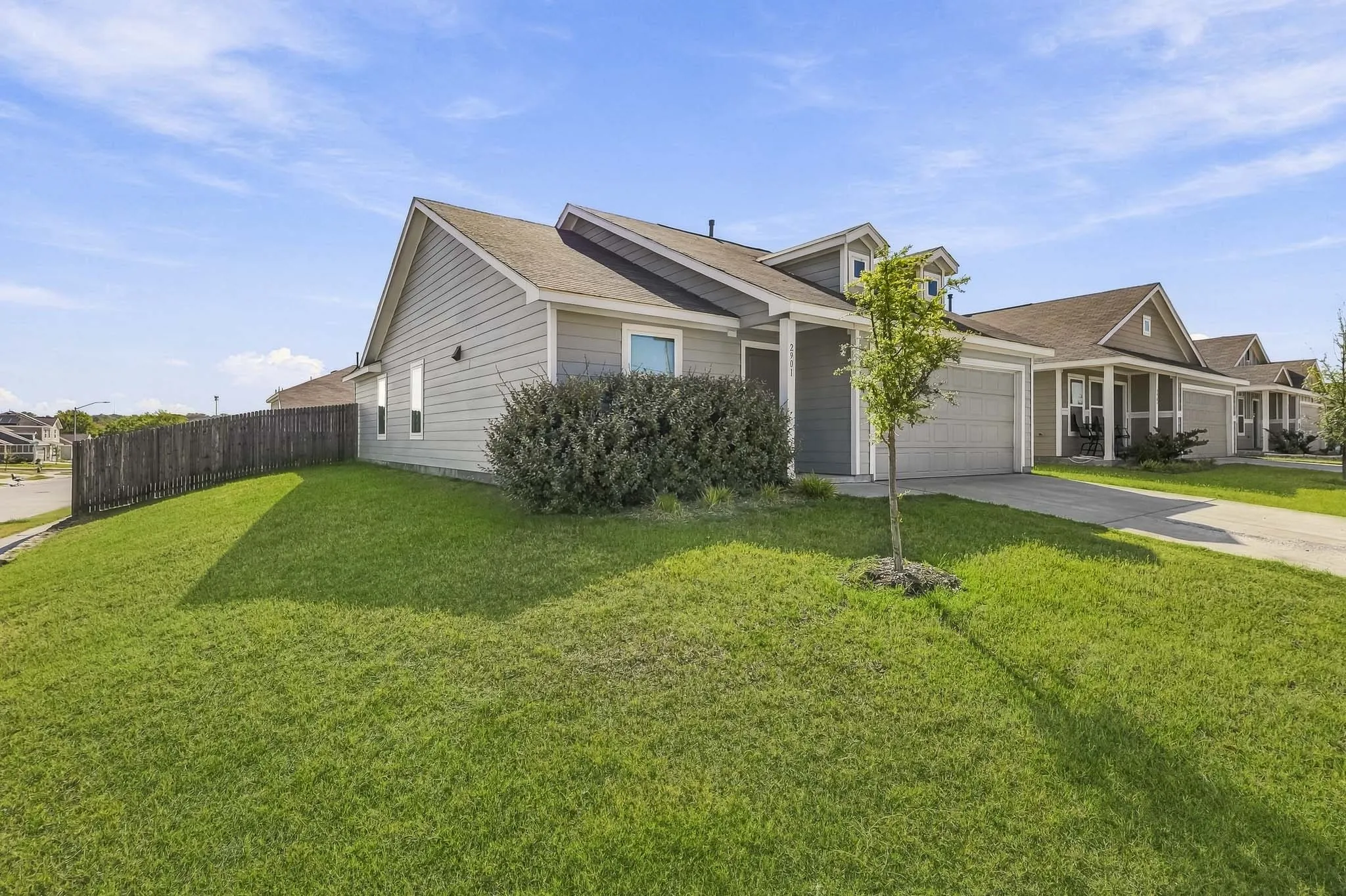 Single-story residence featuring siding exterior, an attached garage, a paved driveway, and a front lawn