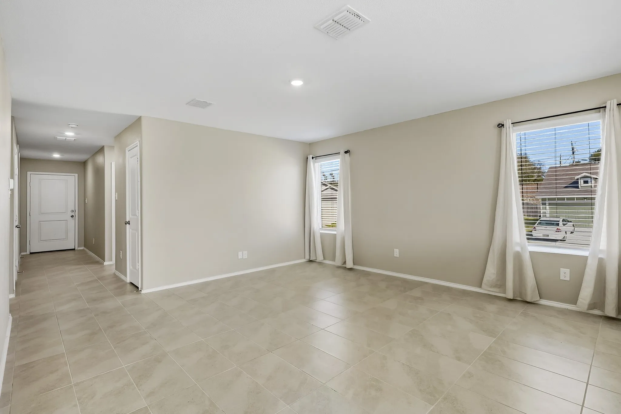 Expansive room with large format tile flooring, recessed lighting, and two windows