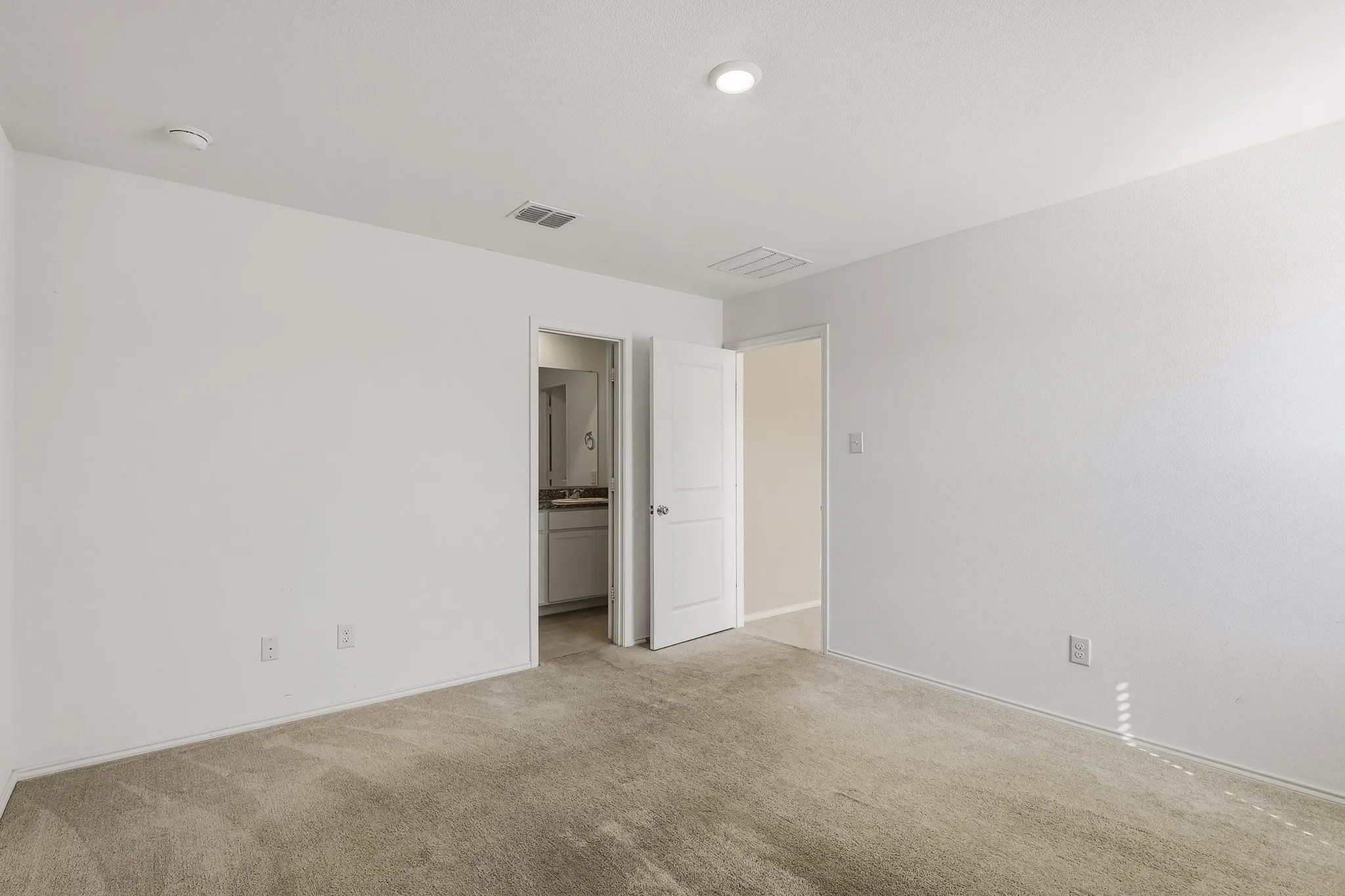 Carpeted room with recessed lighting and a white paneled door
