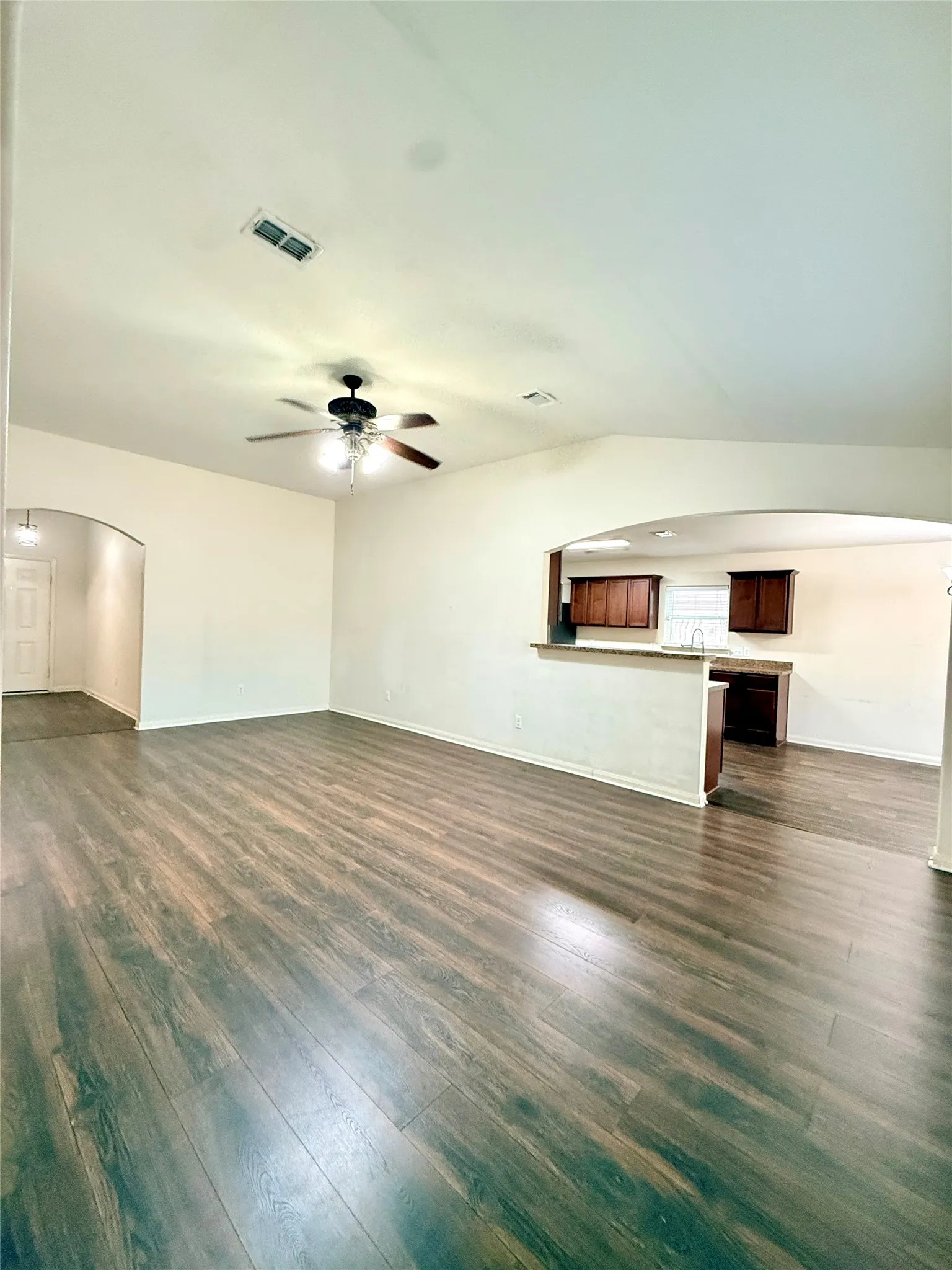 Wood-finish flooring throughout, vaulted ceiling, ceiling fan with integrated lighting, recessed lighting, and kitchen pass-through with countertop