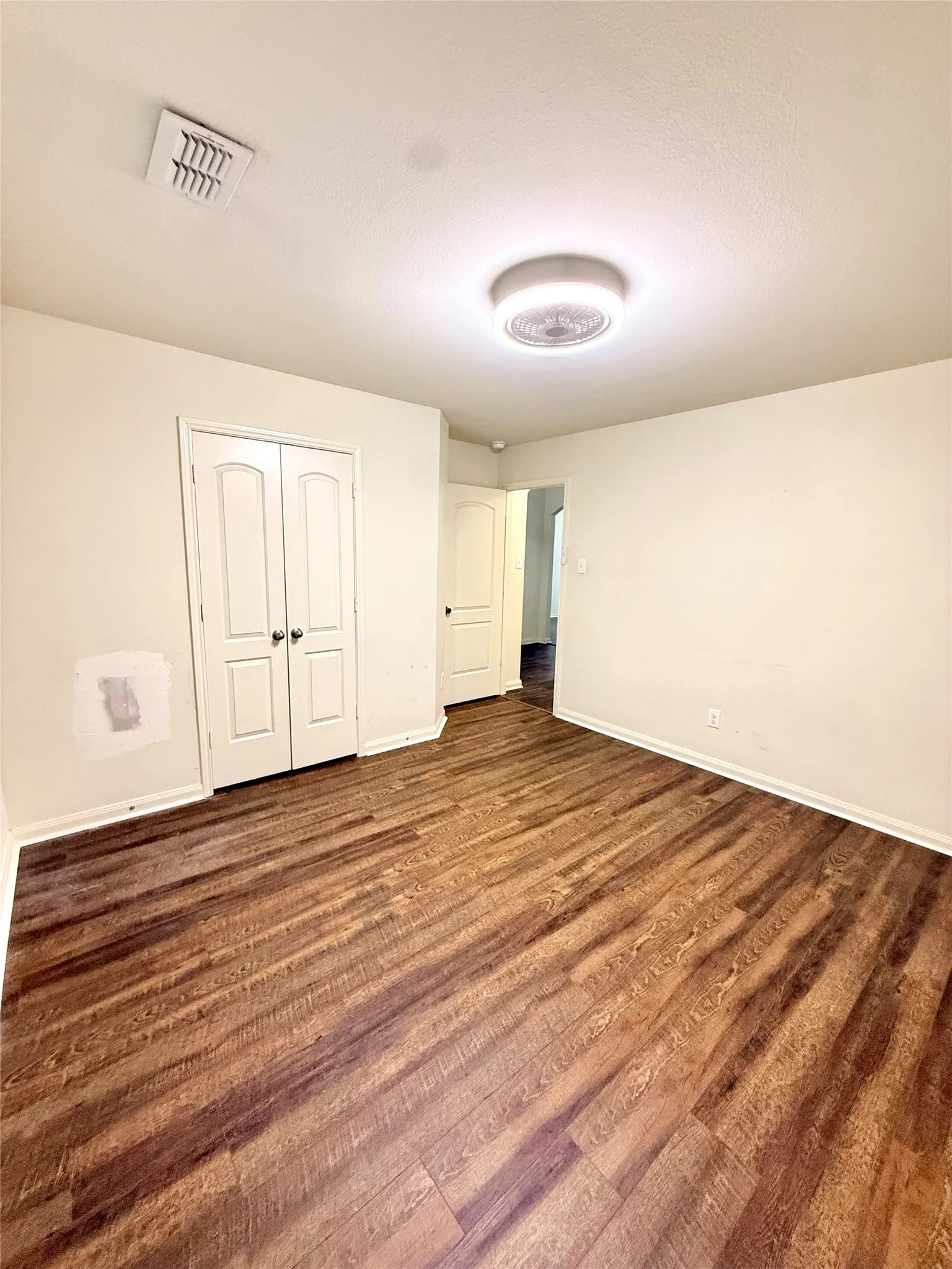 Bedroom 2 Wood-finish flooring, white walls, double panel doors, and a ceiling-mounted light fixture