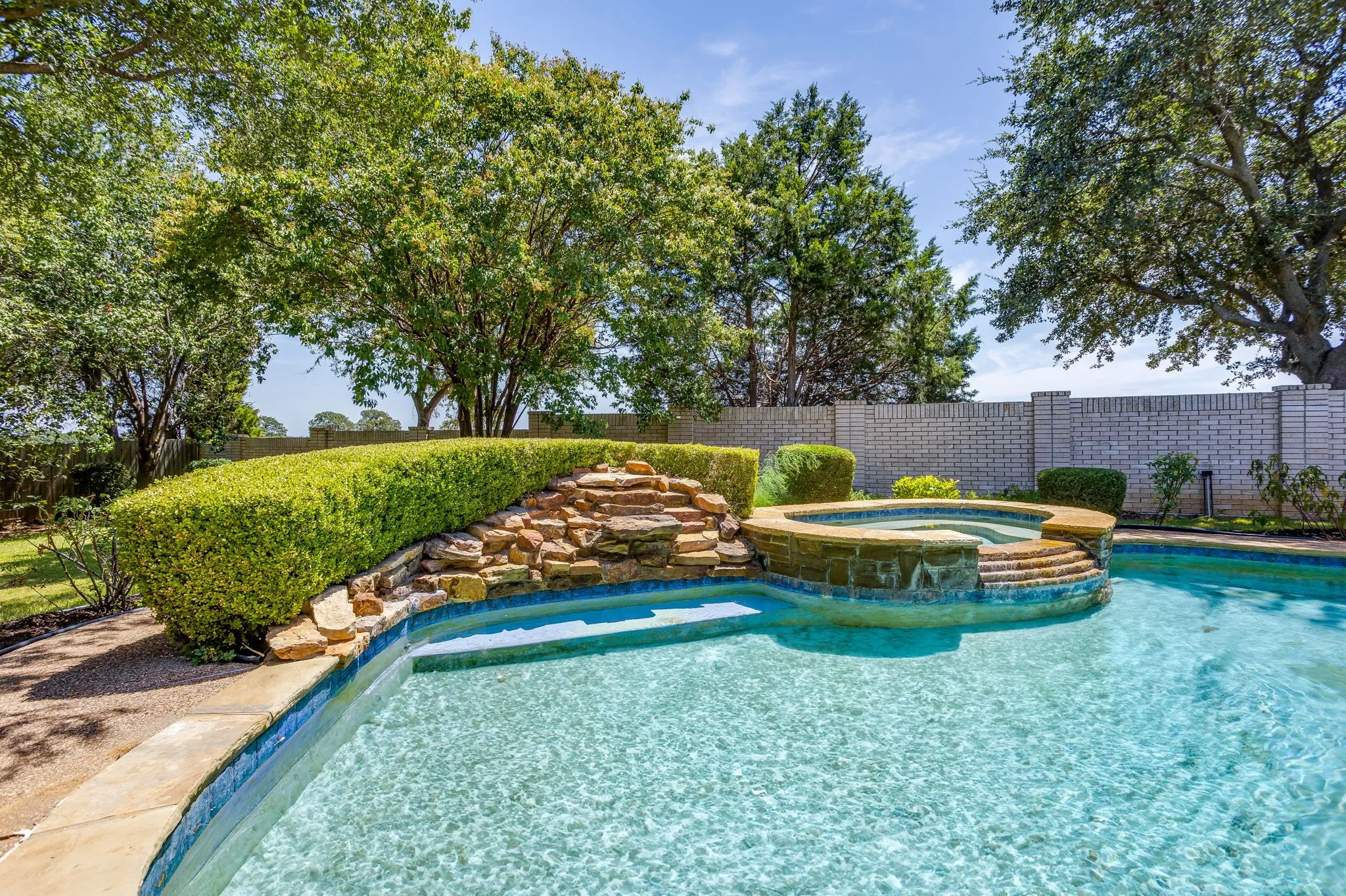 Pool with spa and waterfall fountain.