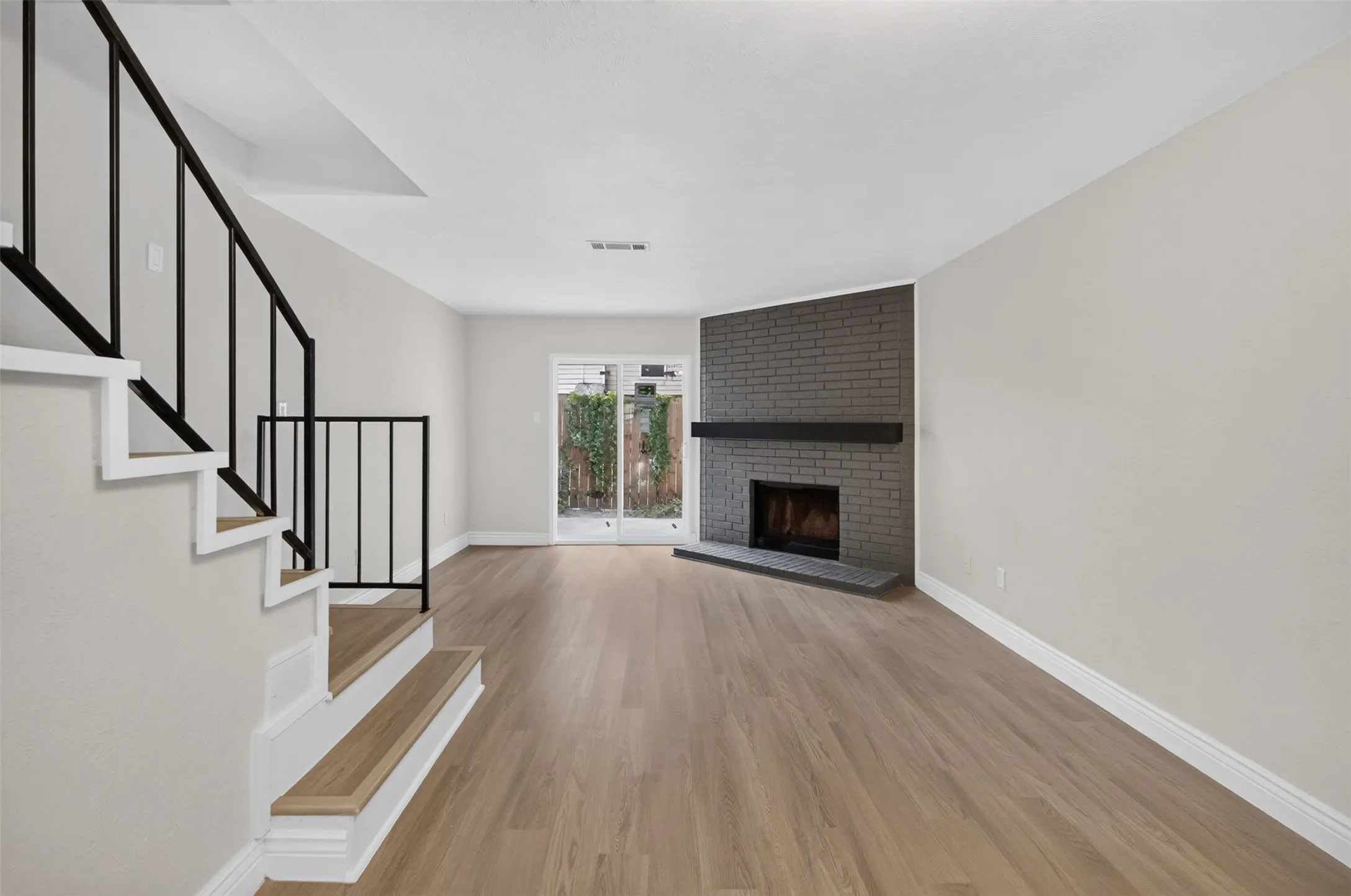 Wood-finish flooring throughout, with a brick-surround fireplace and dark mantel