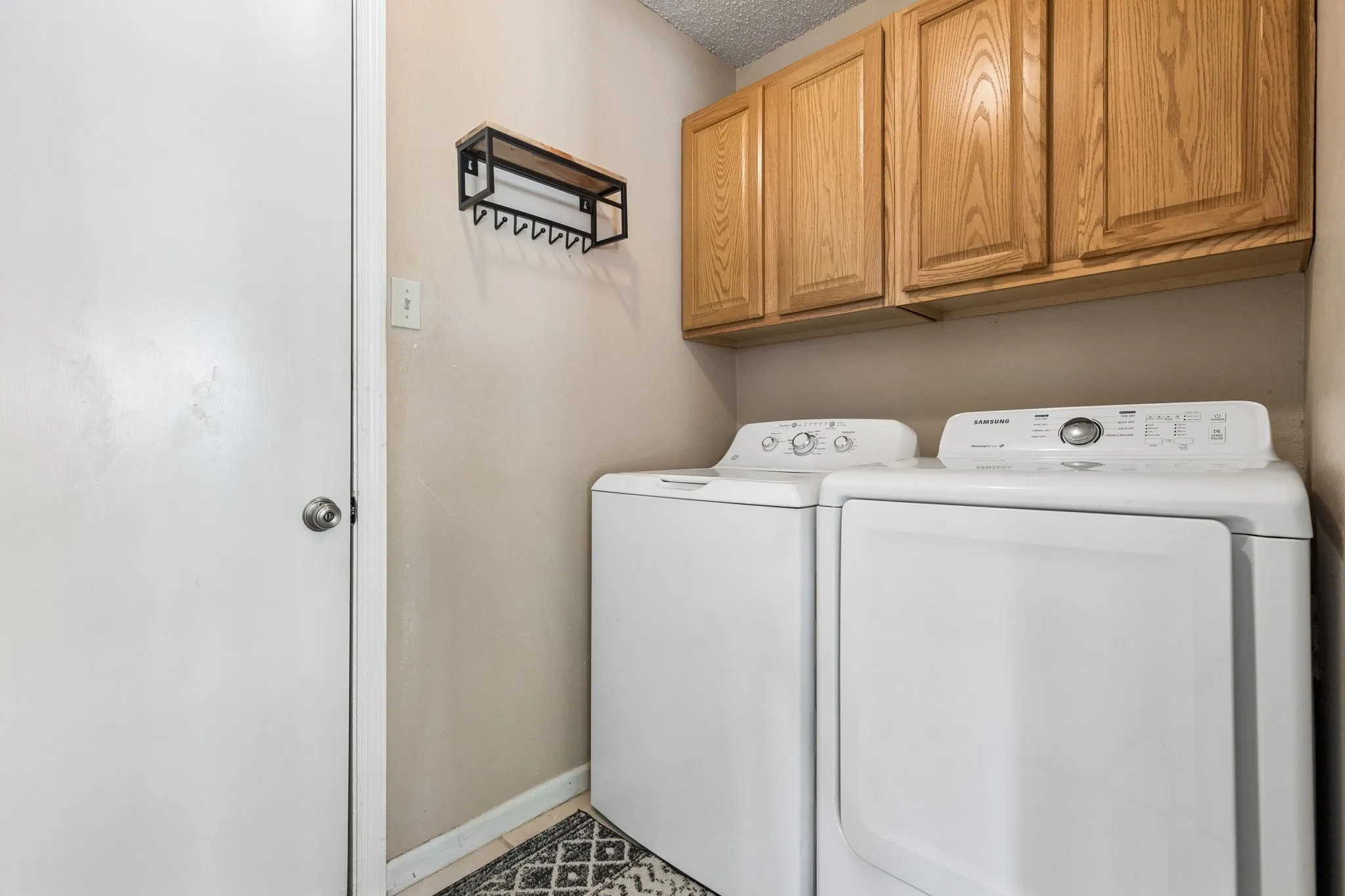 Separate Laundry Room with Full-Size Washer and Dryer and Upper Cabinet Storage
