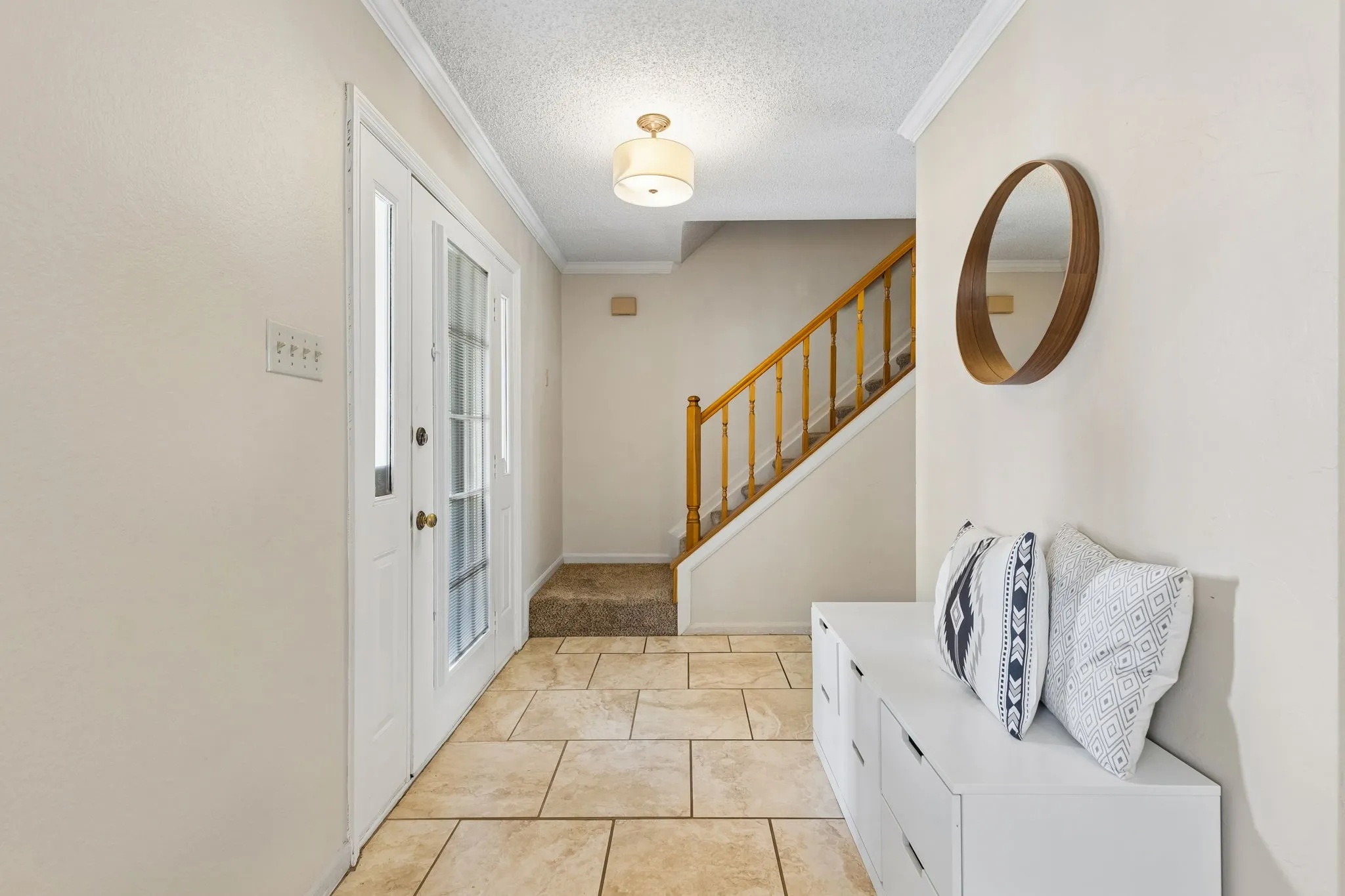 Welcoming Foyer with Tile Flooring, Crown Molding and Staircase Leading to the Second Floor