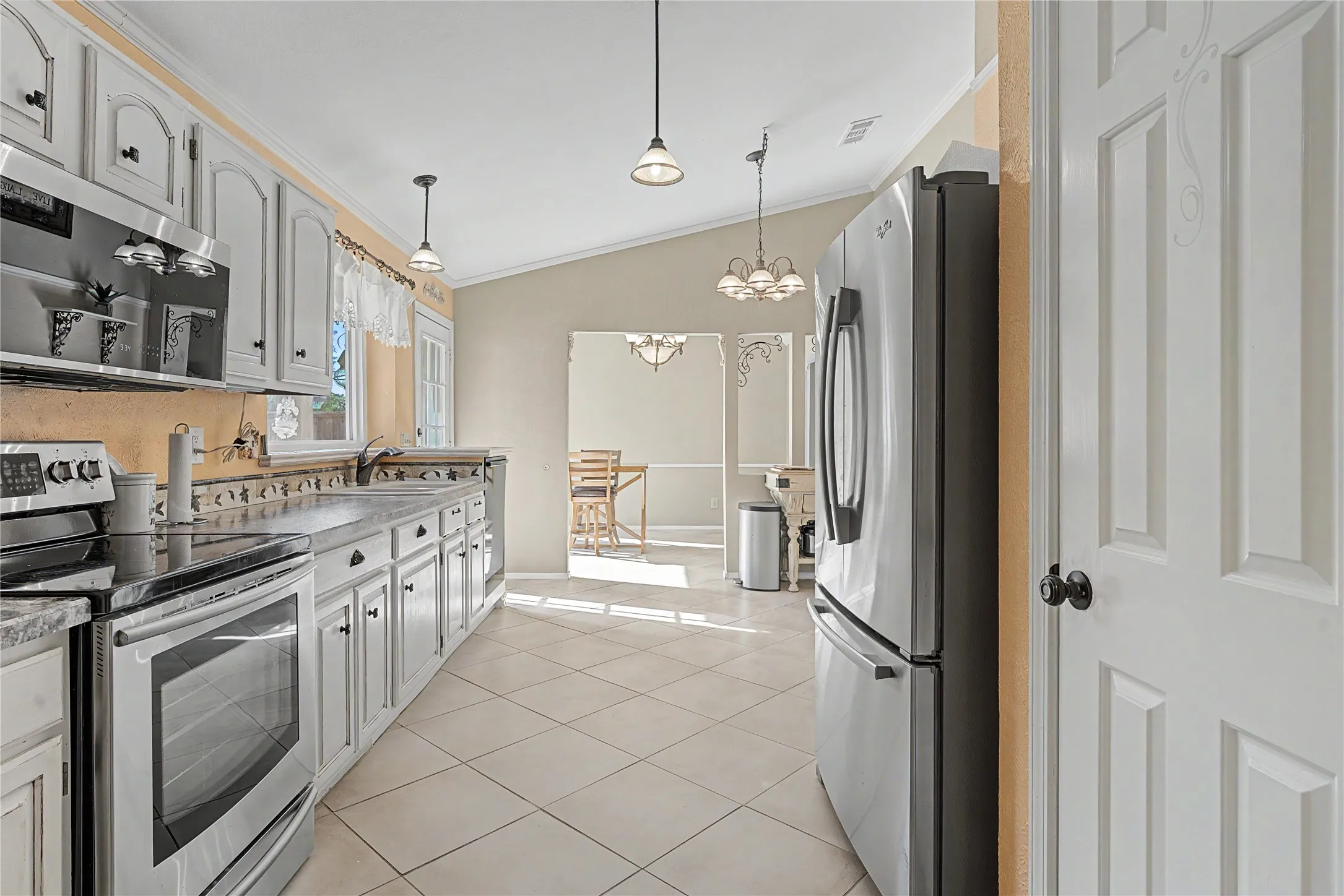 Kitchen featuring stainless steel appliances, light-toned cabinetry, solid surface countertops, and tile flooring
