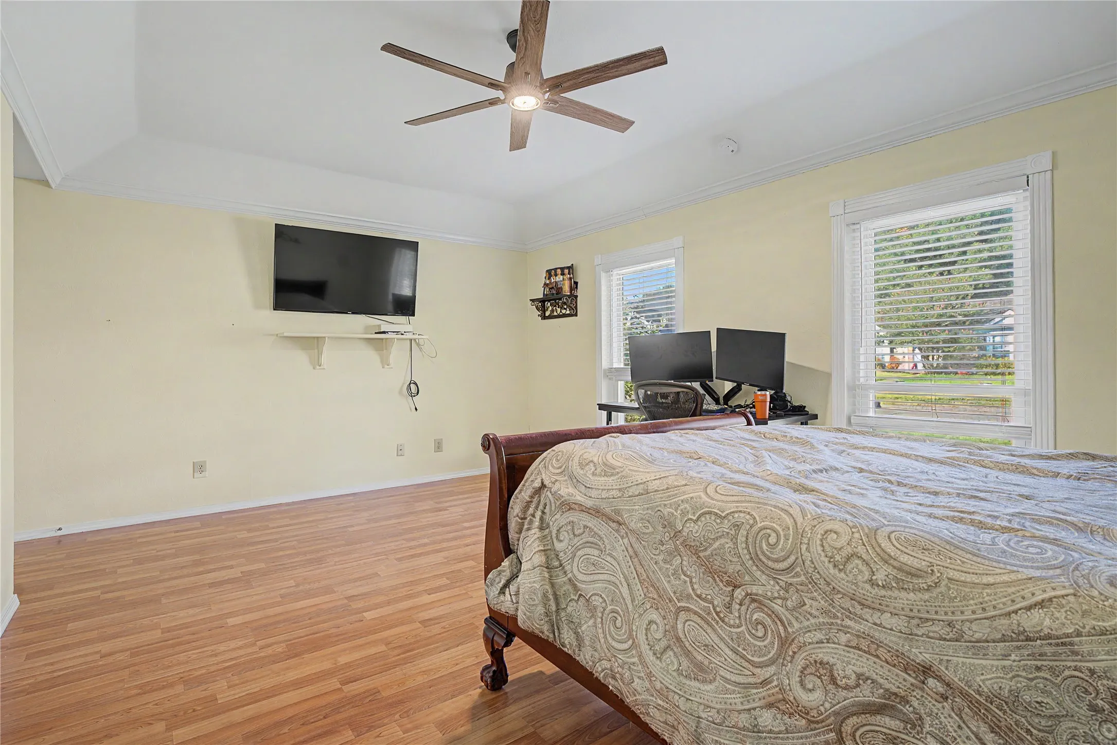 Tray ceiling with crown molding, wood-finish flooring, and multiple windows
