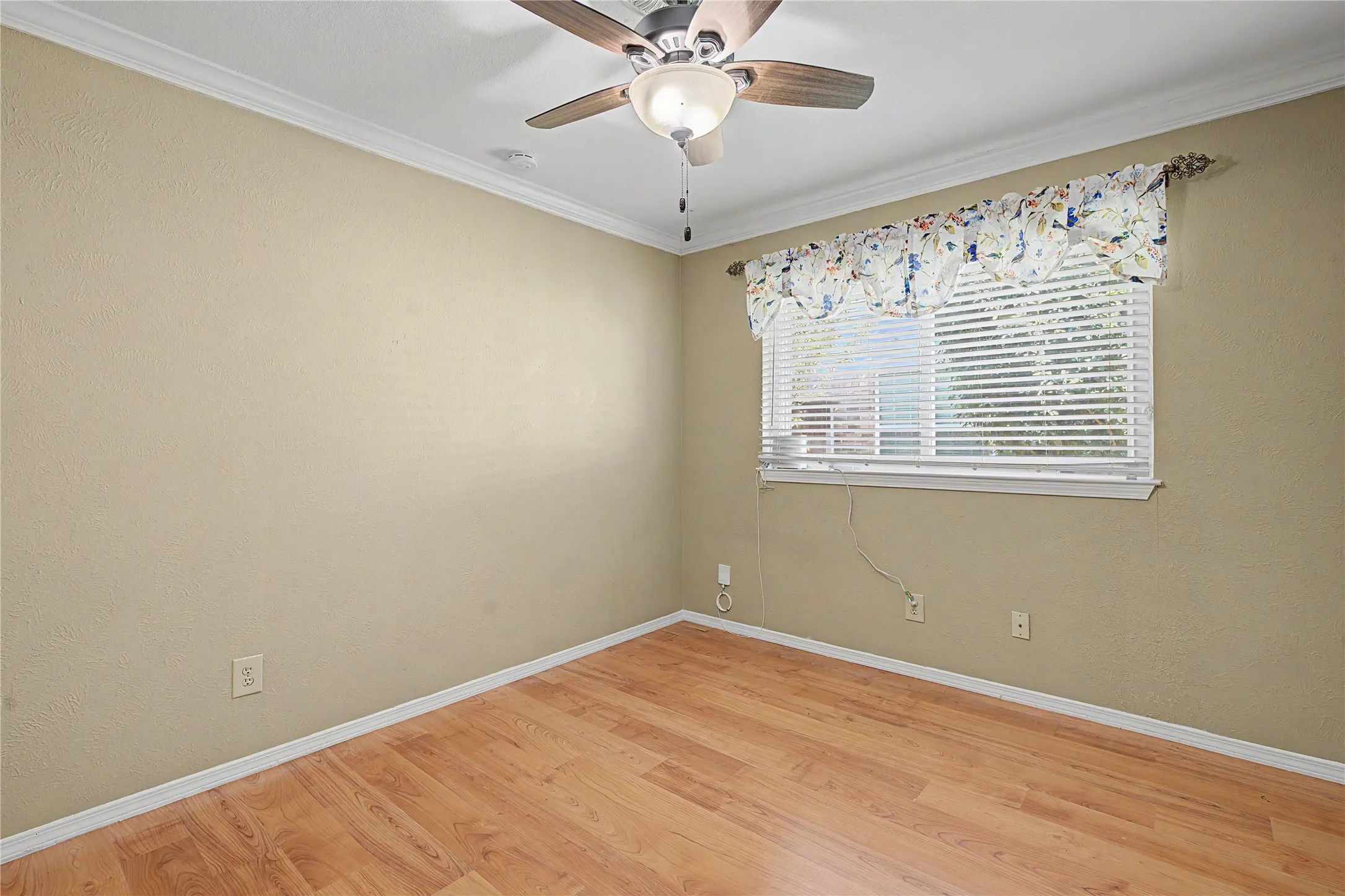 Wood-finish flooring, ceiling fan with integrated lighting, and crown molding