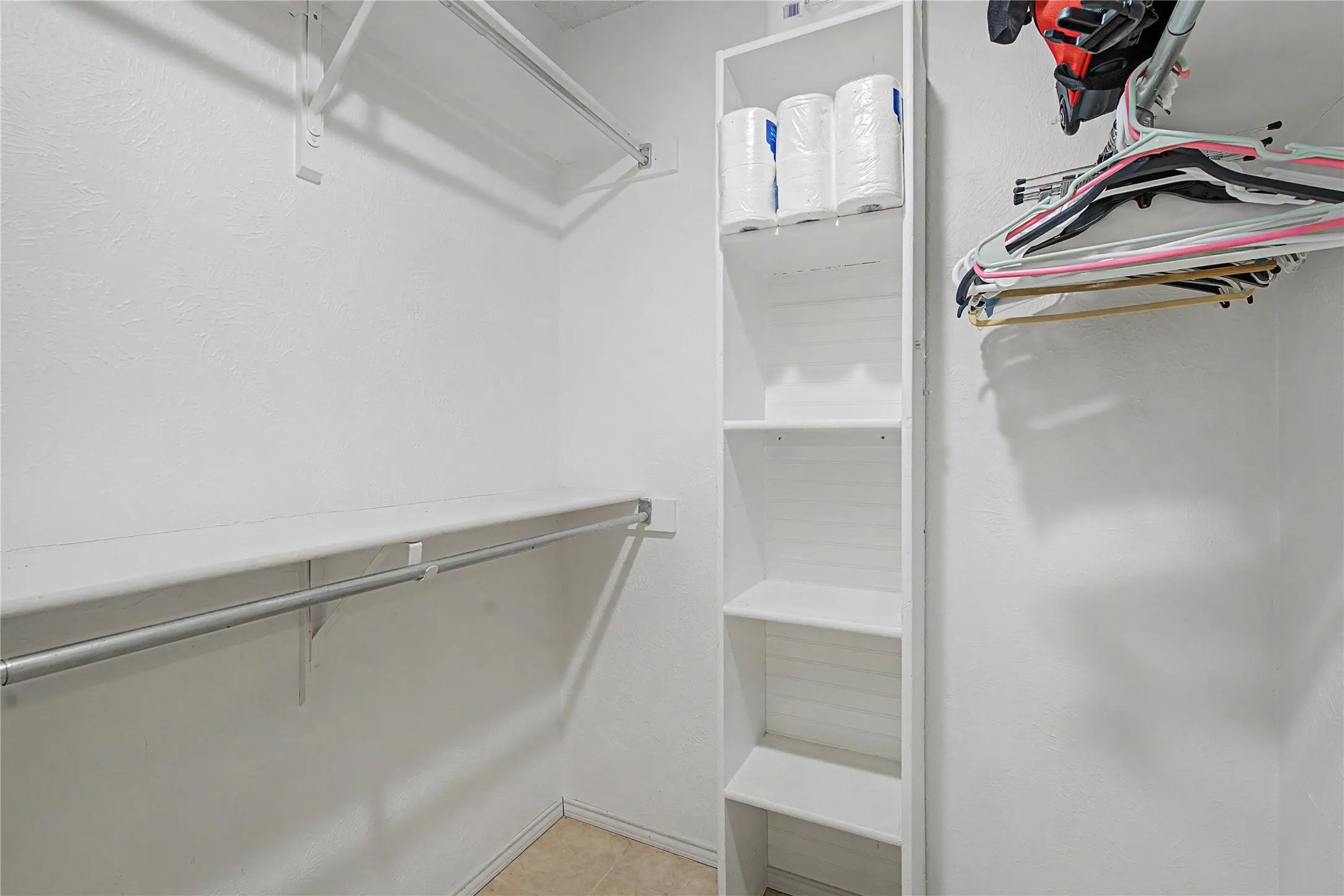 Walk-in closet featuring built-in shelving, multiple hanging rods, and neutral wall tones