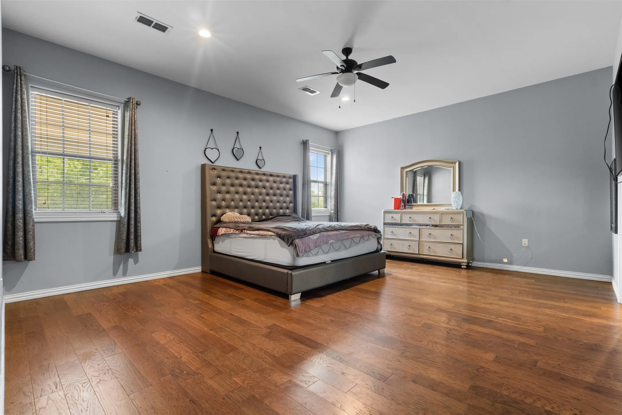 Hardwood flooring, recessed lighting, ceiling fan, multiple windows, and light gray wall paint