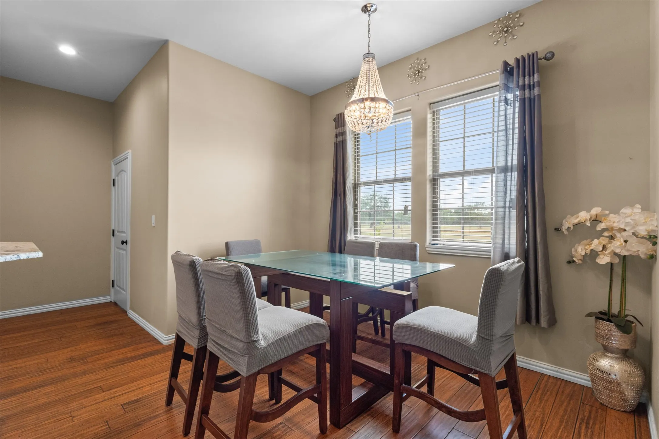 Wood-finish flooring, warm neutral wall tones, and a crystal chandelier