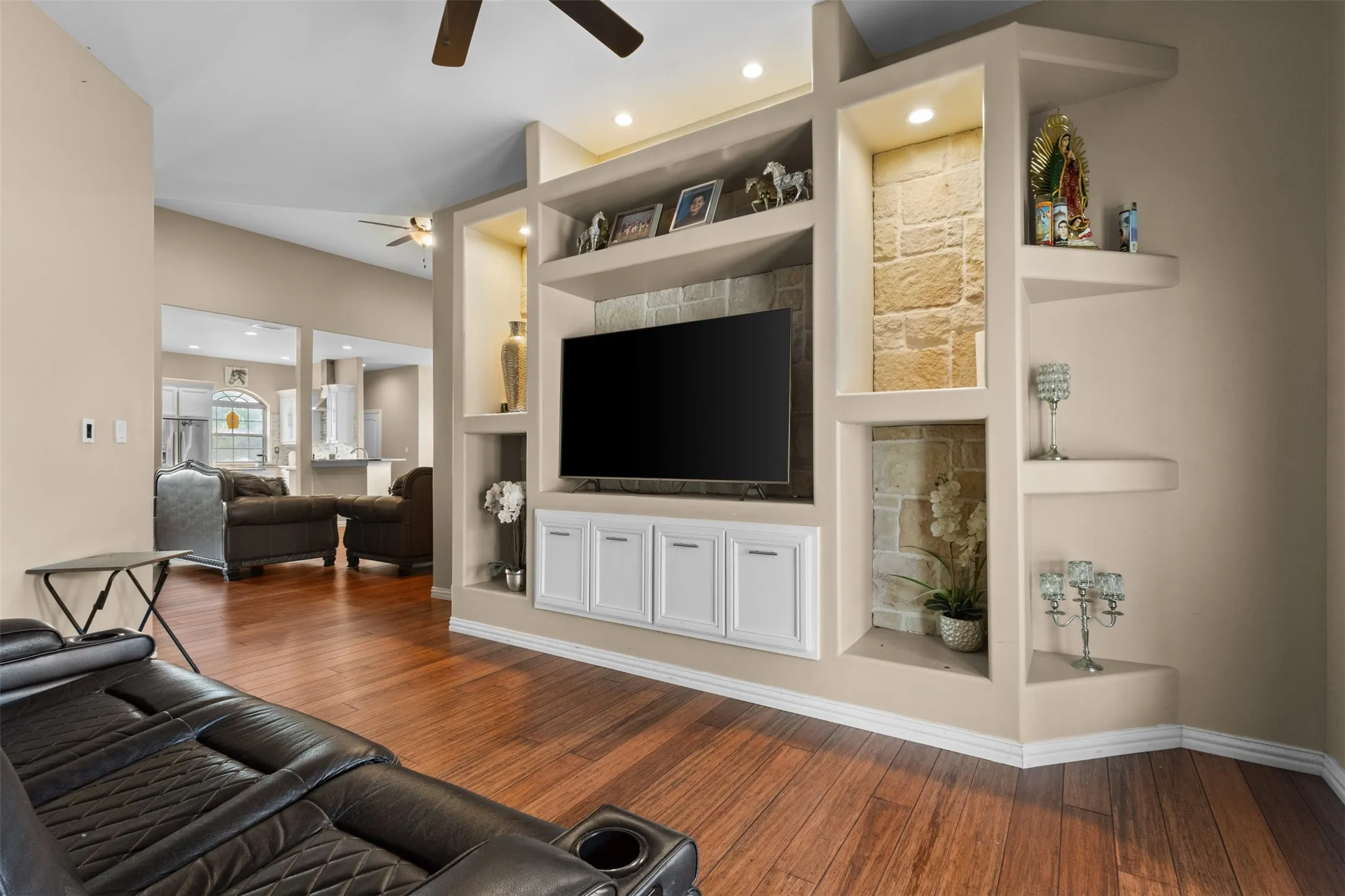 Built-in media center with recessed lighting, stone-finish accents, white cabinetry, wood-finish flooring, and vaulted ceilings
