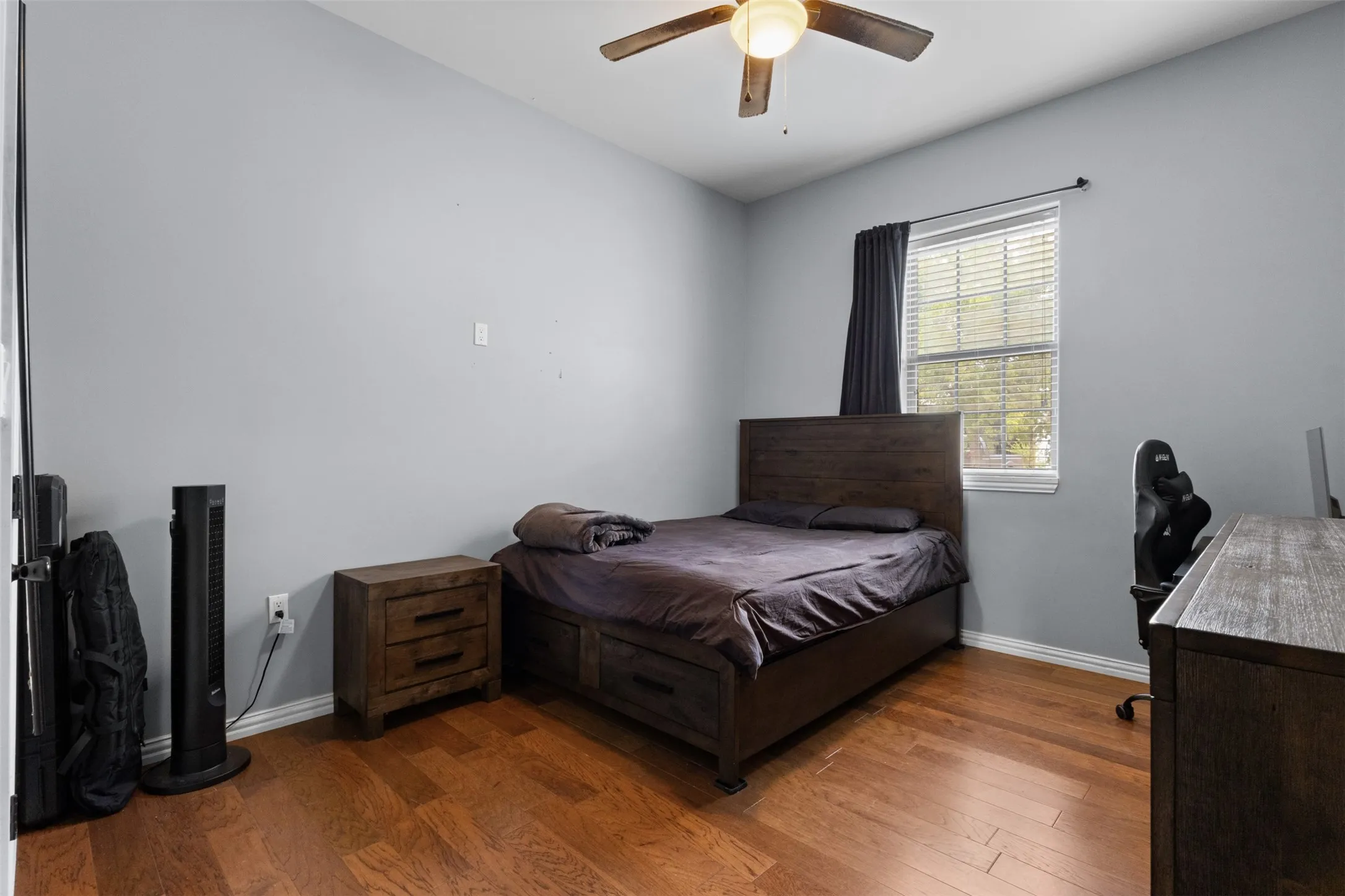 Wood-finish flooring, single window with blinds, ceiling fan with integrated lighting, and neutral wall paint