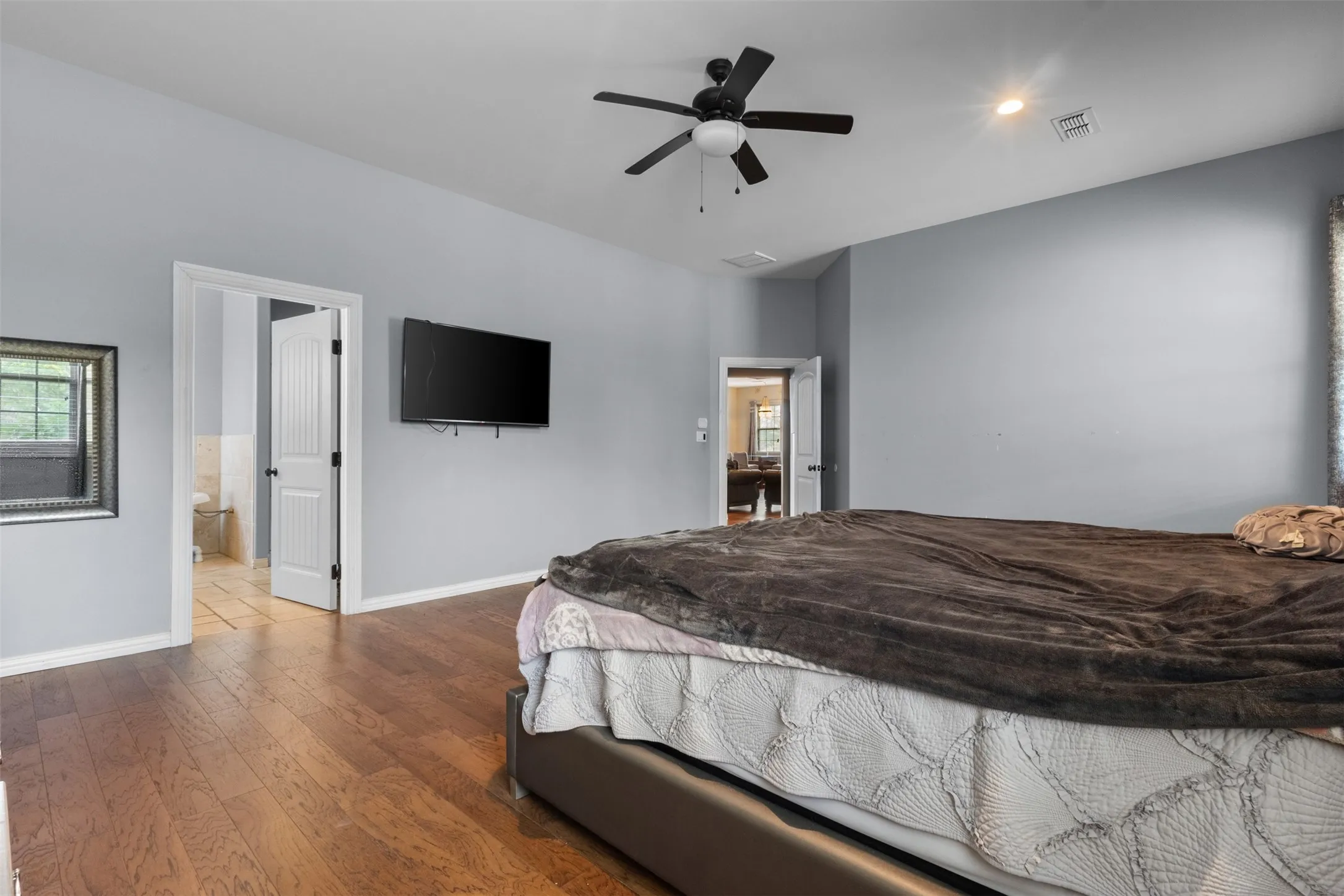 Vaulted ceilings, recessed lighting, ceiling fan, wood-finish flooring, and a framed window