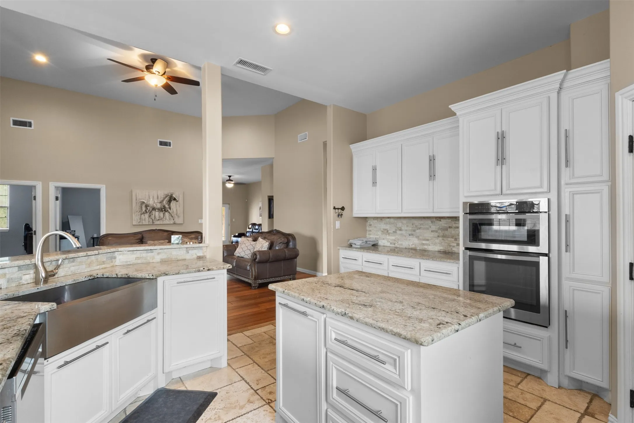 Kitchen featuring white cabinetry, stone countertops, a large stainless-steel sink, stainless steel built-in double oven, and tiled flooring
