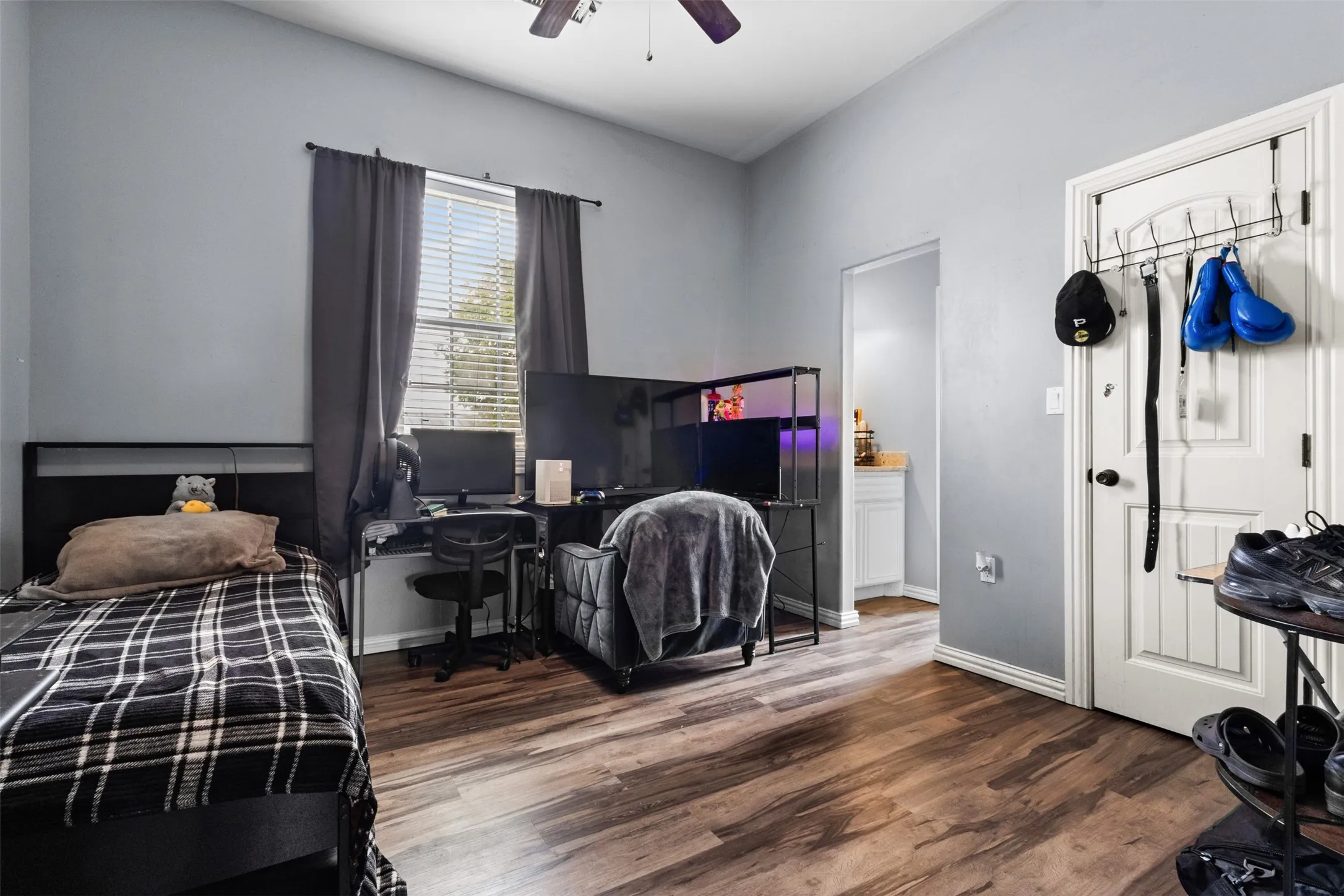 Wood-finish flooring, high ceilings, ceiling fan, and window with blinds