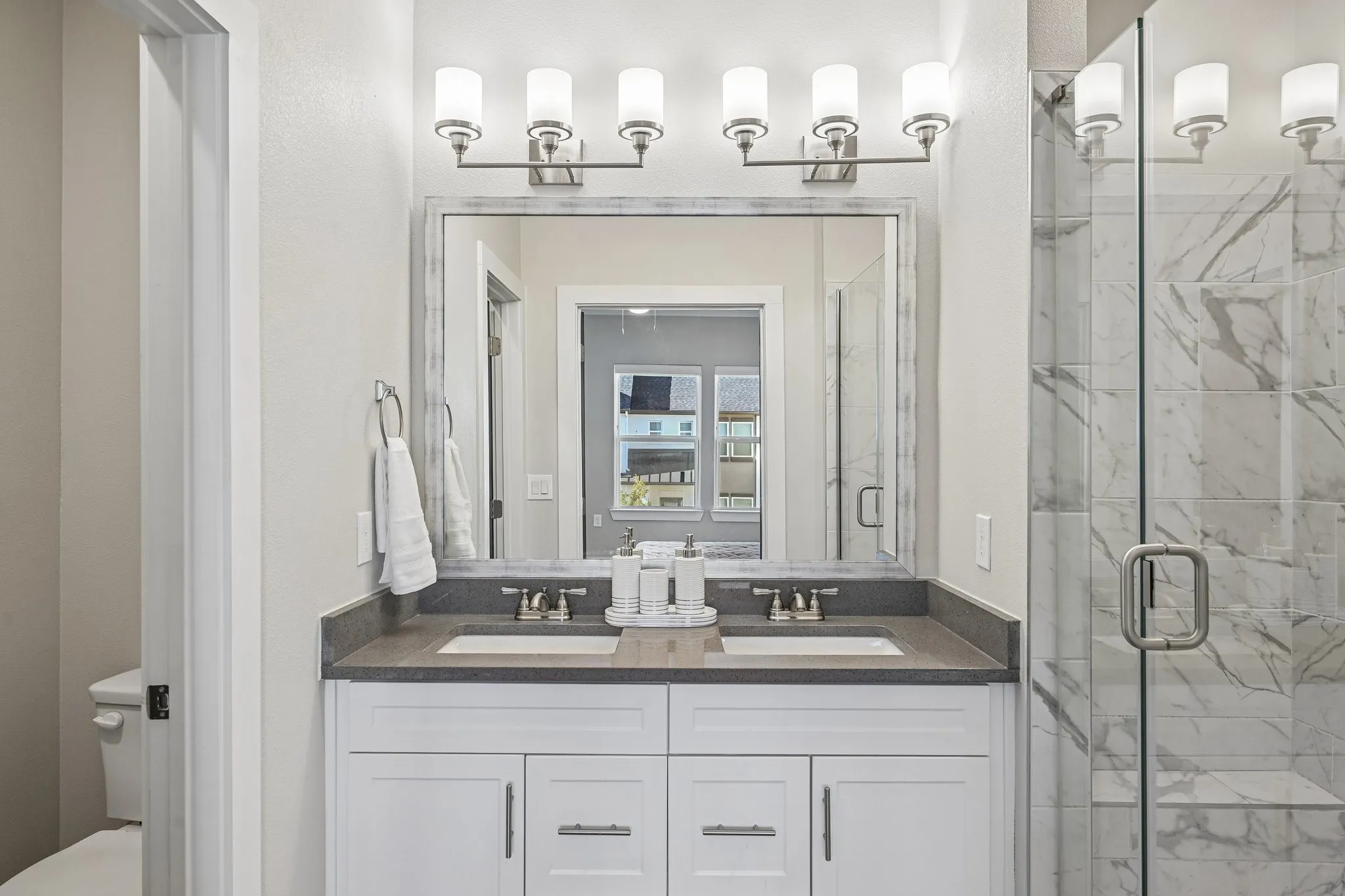 Double vanity with white cabinetry, dual undermount sinks, and a dark stone countertop