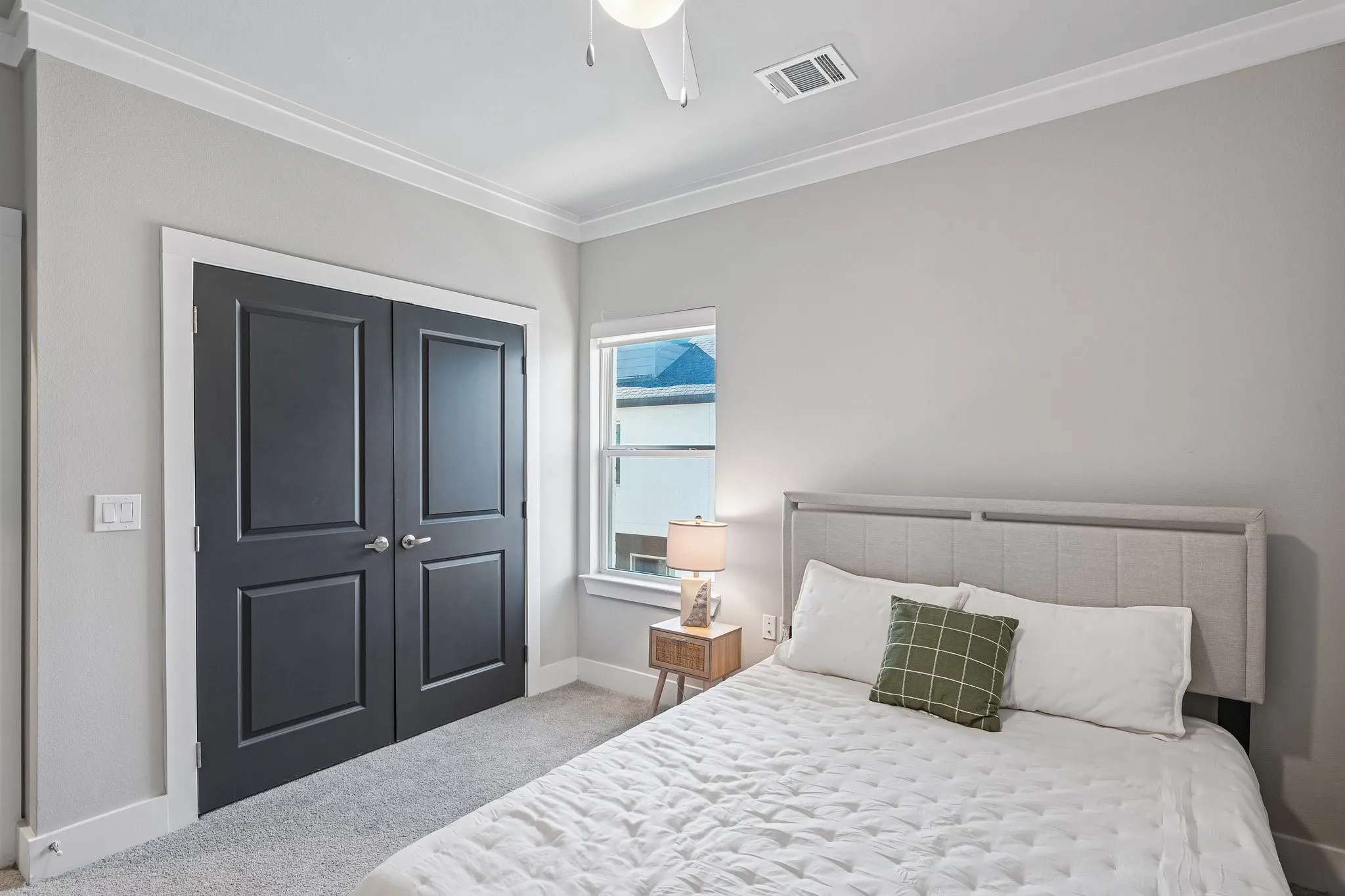 Neutral wall paint, crown molding, gray carpet flooring, dark paneled bi-fold doors, and a ceiling fan