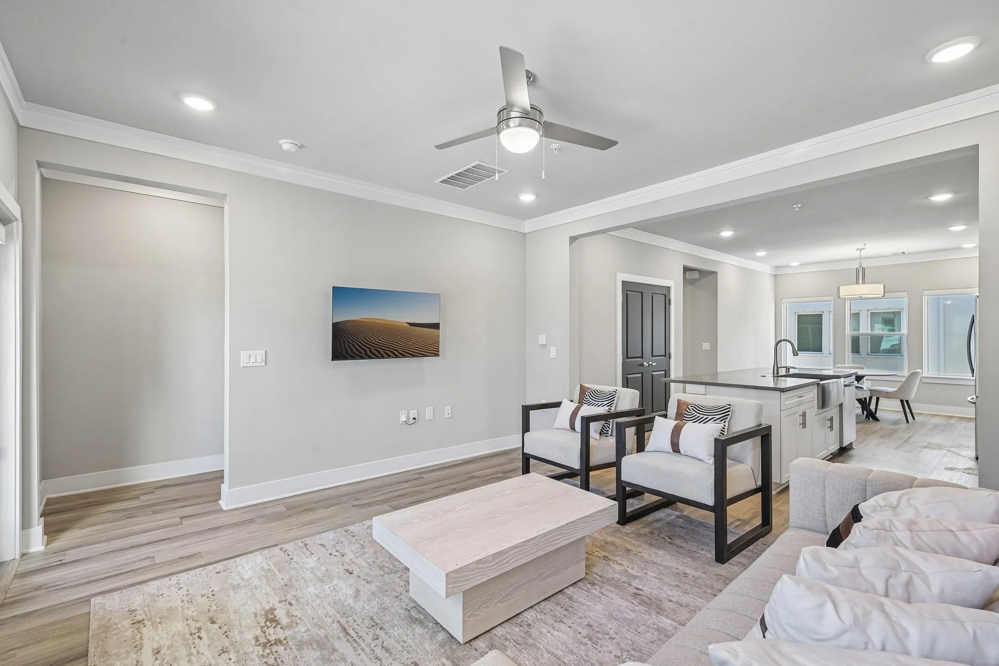 Recessed lighting, wood-finish flooring, ceiling fan, crown molding, and a kitchen island with sink
