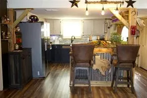 Wood-finish flooring with a kitchen featuring upper white cabinetry, lower dark cabinetry, and a countertop