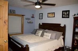 Ceiling fan with integrated lighting, wood-finish door, wood-finish window trim, and wood-finish headboard