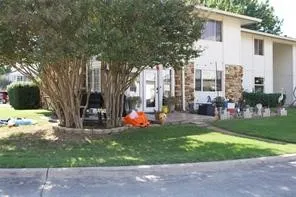 White exterior with stone accents and a mature tree