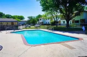 Outdoor swimming pool with concrete surround, perimeter fencing, and an adjacent covered patio area