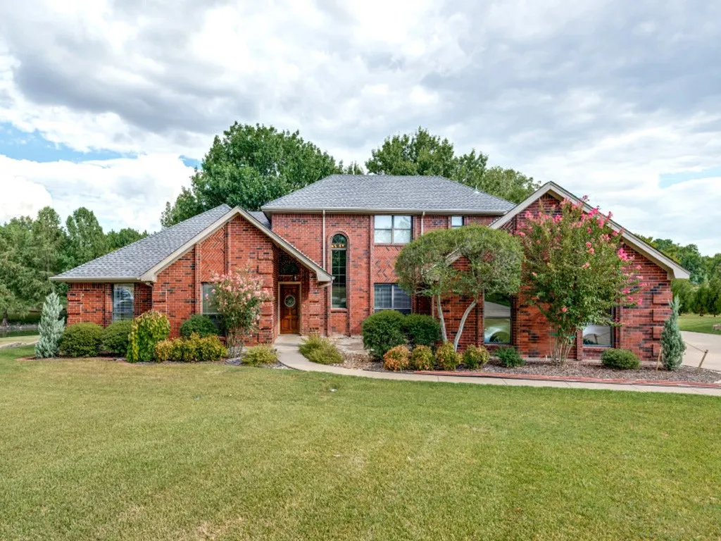 Brick exterior with a gabled roofline, arched front window, and mature landscaping