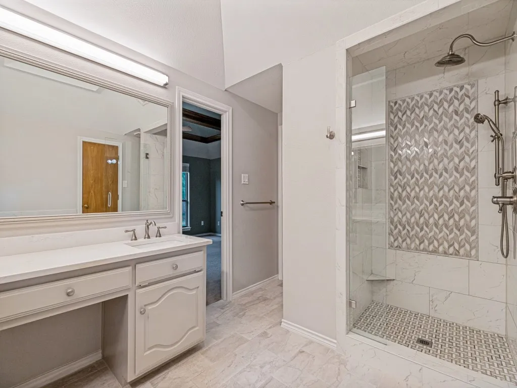 Walk-in shower with chevron mosaic tile accent, glass enclosure, and tiled flooring