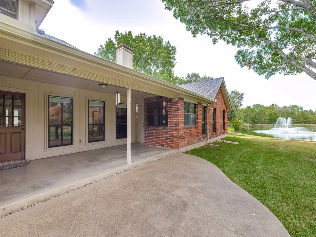 Back porch with expansive view of the back yard with mature trees overlooking the pond