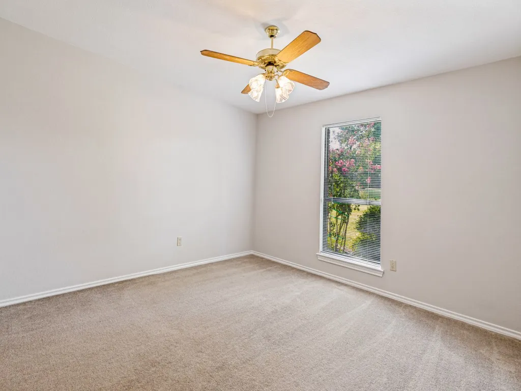 Wall-to-wall carpeting, ceiling fan with light fixture, and window with natural light