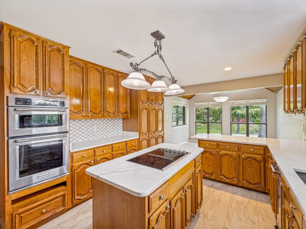 Kitchen featuring wood cabinetry, Quartz counters, a tiled backsplash, and stainless steel microwave, oven and trash compactor