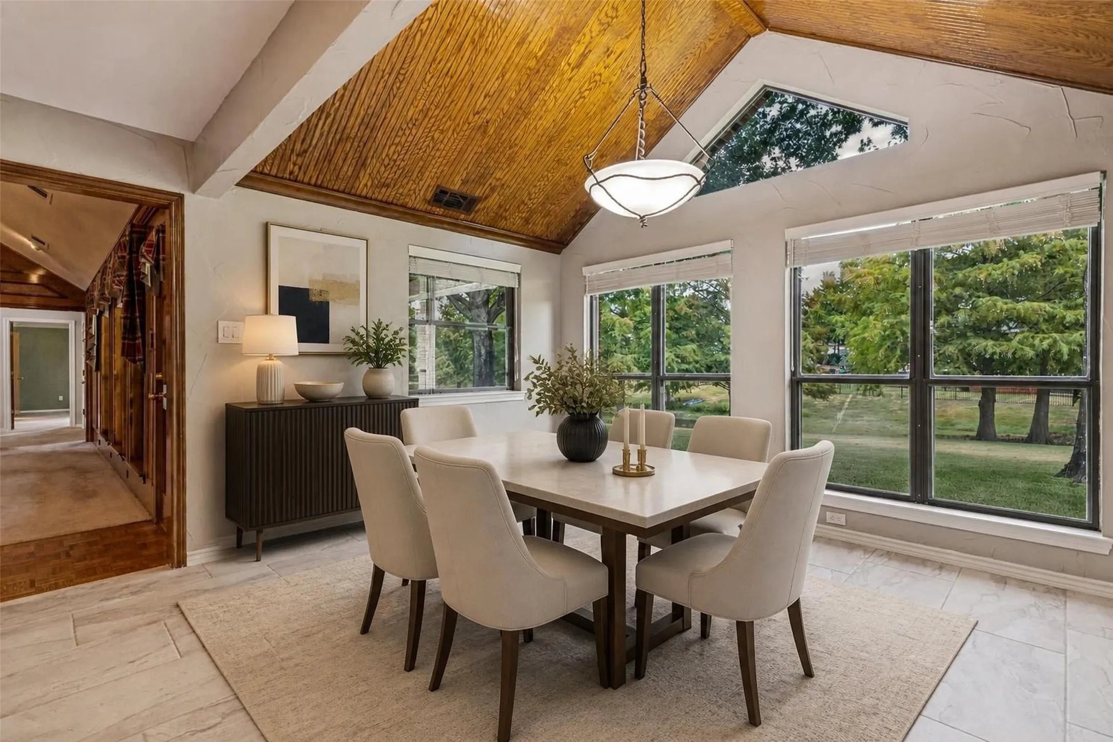 Virtually Staged - Vaulted wood-paneled ceiling with exposed beam, large windows, transom window, and tile flooring
