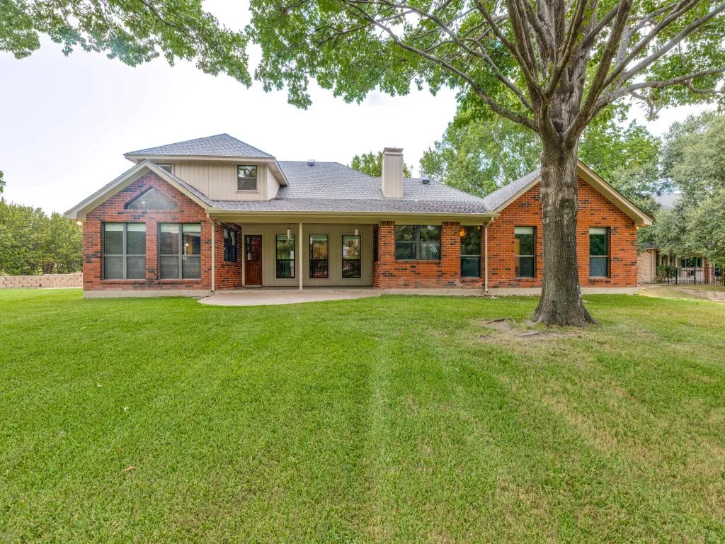 Expansive rear lawn with mature trees and a covered patio