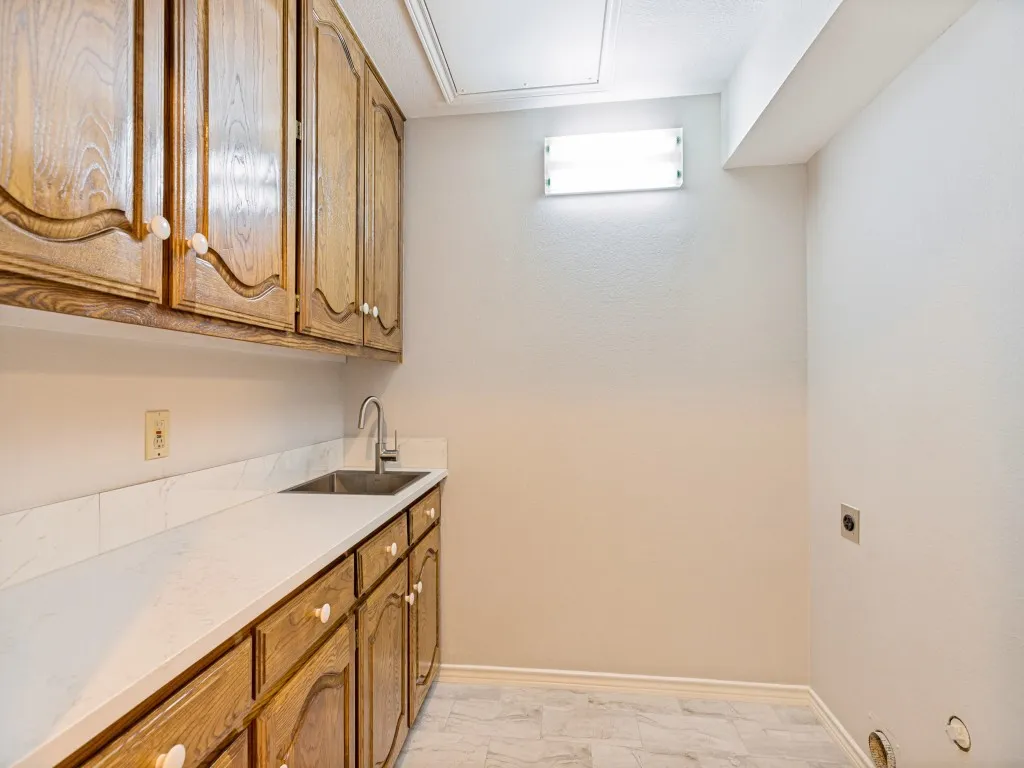 Extensive cabinetry, quartz counters, stainless steel sink with gooseneck faucet, light-toned tile flooring