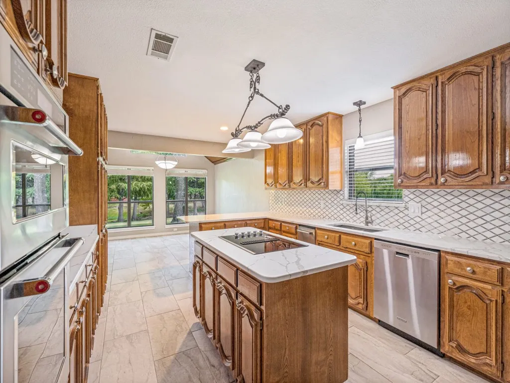 Kitchen featuring wood cabinetry, KitchenAid stainless steel appliances, Quartz counters, a tiled backsplash.