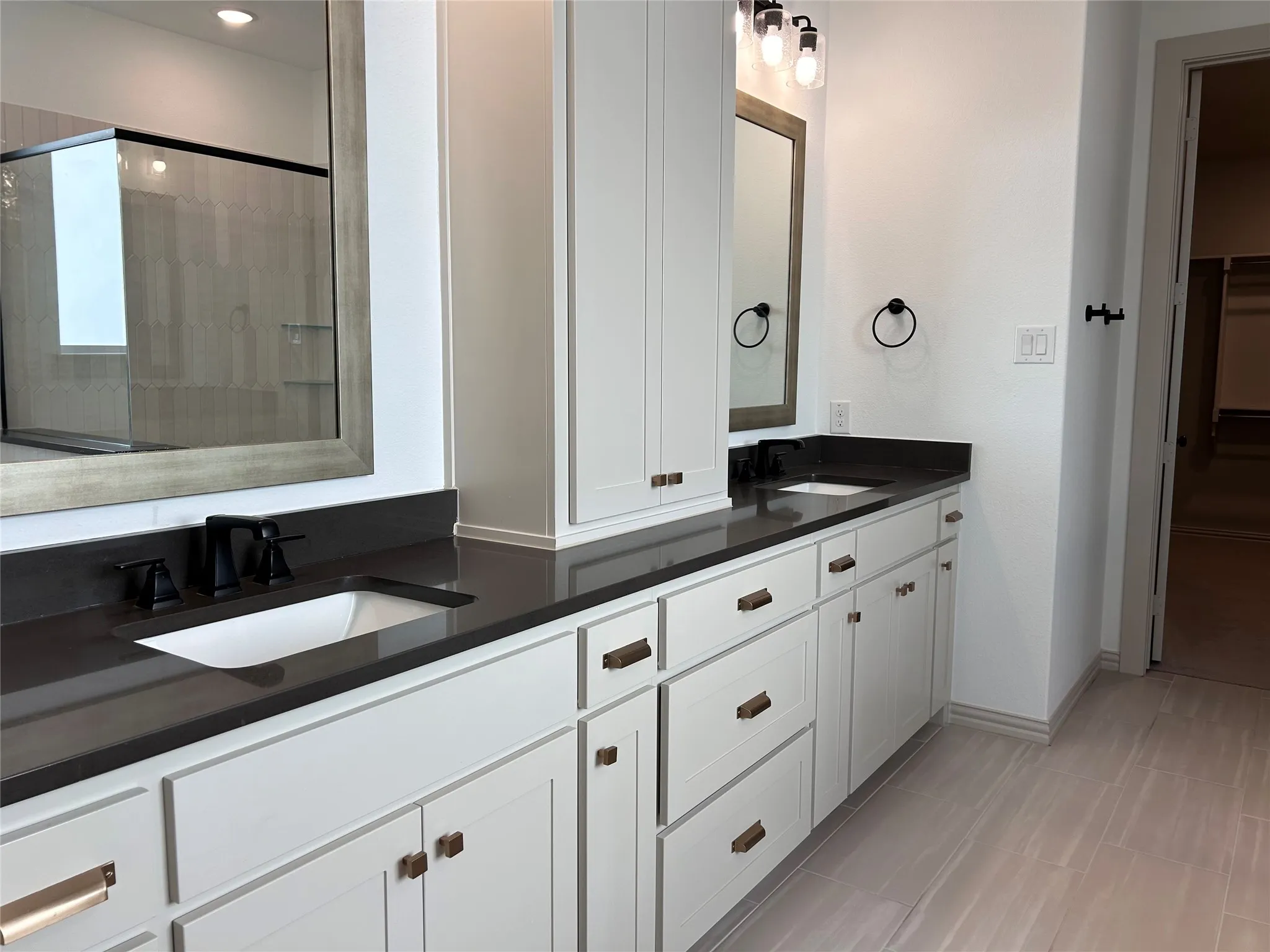Dual vanity with dark countertops, undermount sinks, and matte black fixtures