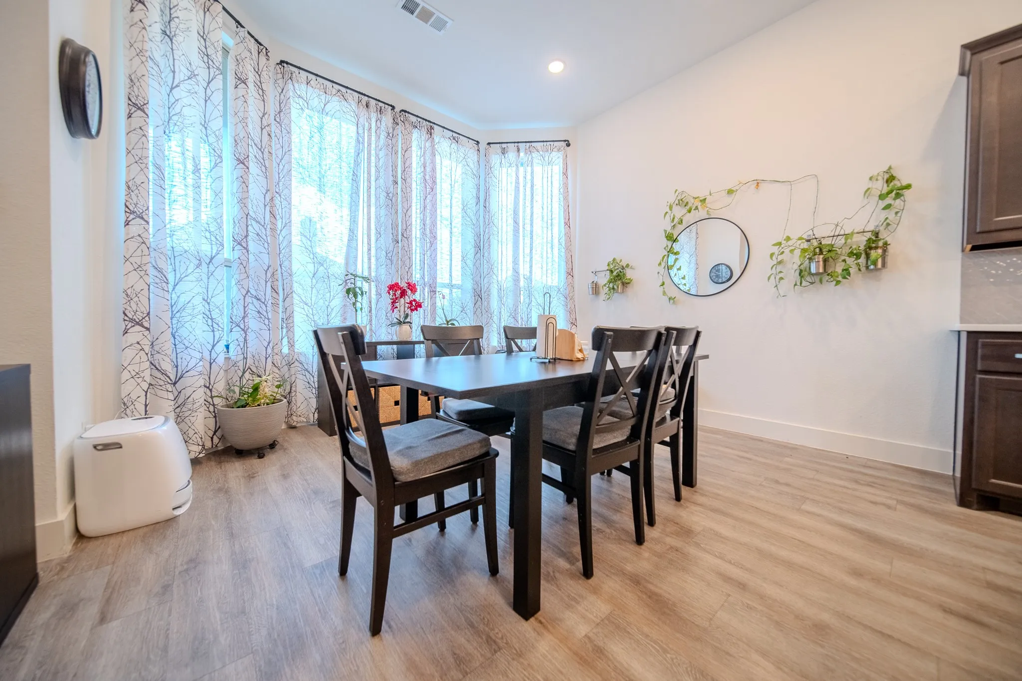 Vaulted ceiling with recessed lighting, wood-finish flooring, bay window with decorative sheers, built-in cabinetry, and tile backsplash