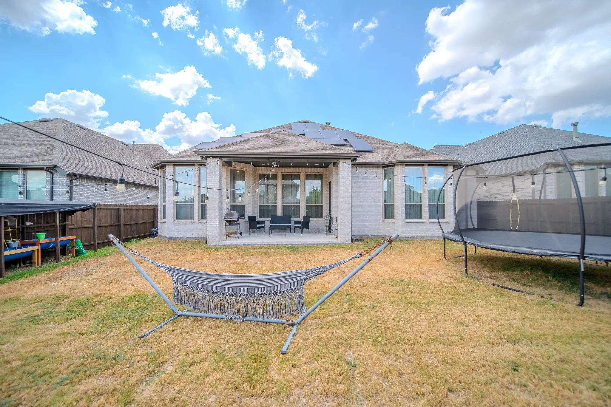 Rear exterior featuring a covered patio, solar panels, and multiple large windows