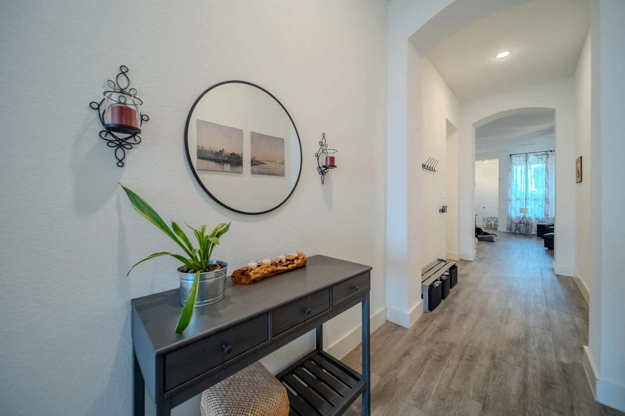 Archway leading to a brightly lit interior, featuring wood-finish flooring and recessed lighting