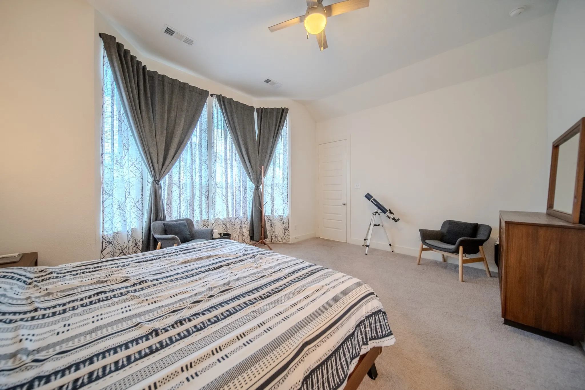 Expansive room with high ceilings, plush carpeting, and a ceiling fan