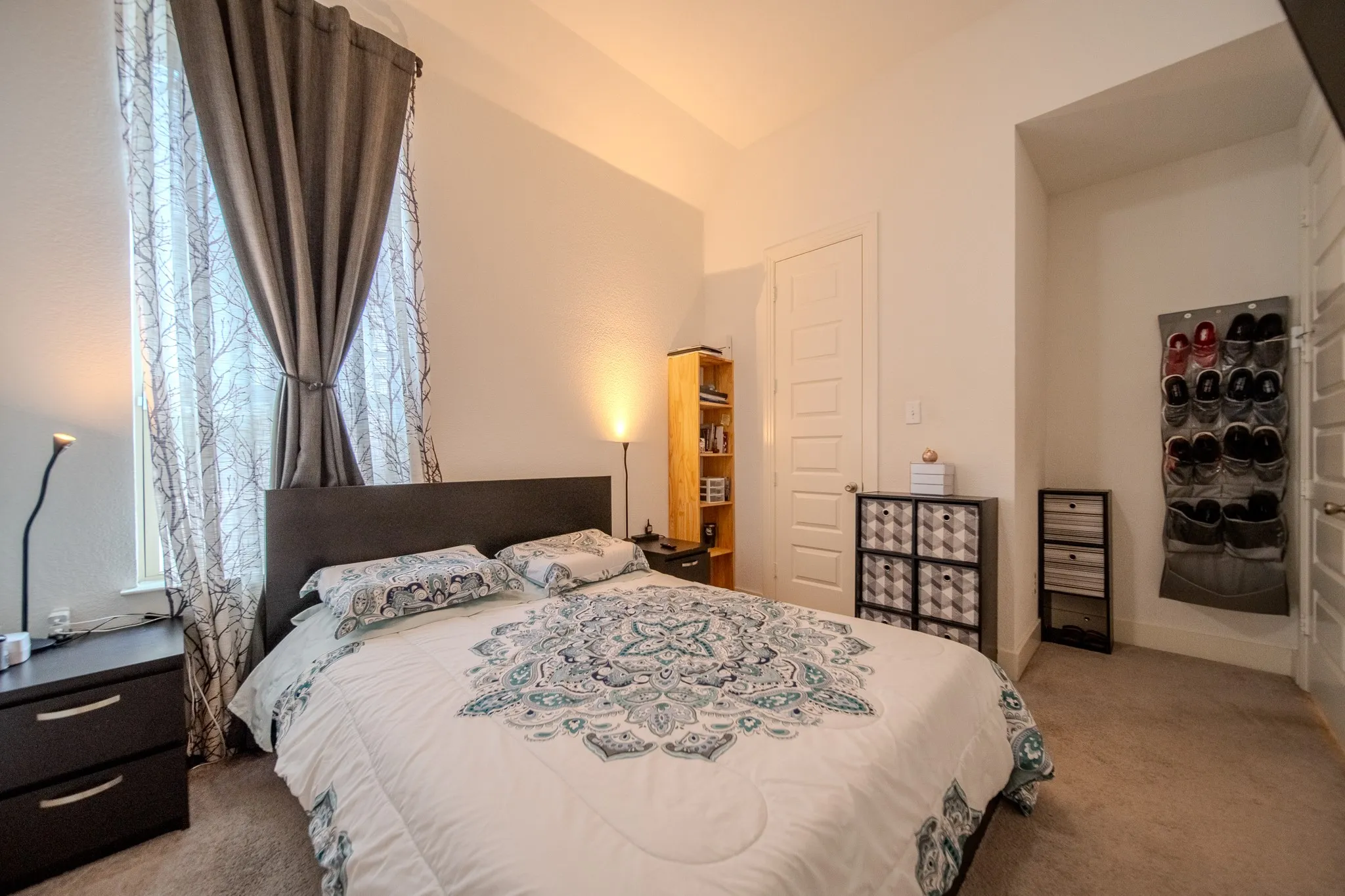 Recessed window with sheer and blackout drapery, textured carpeting, and high ceilings