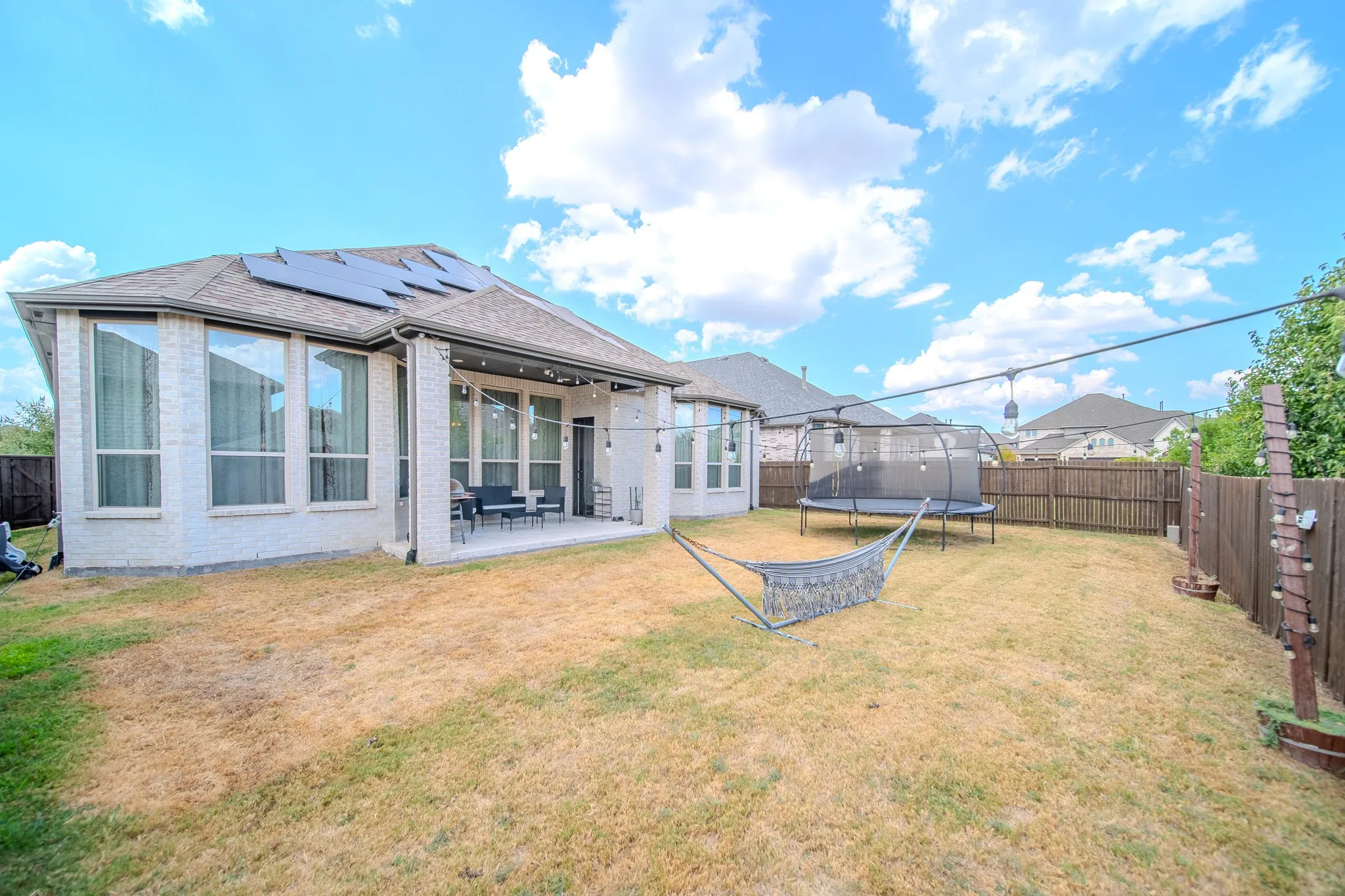 Expansive backyard with a covered patio, solar panels, and a wood privacy fence