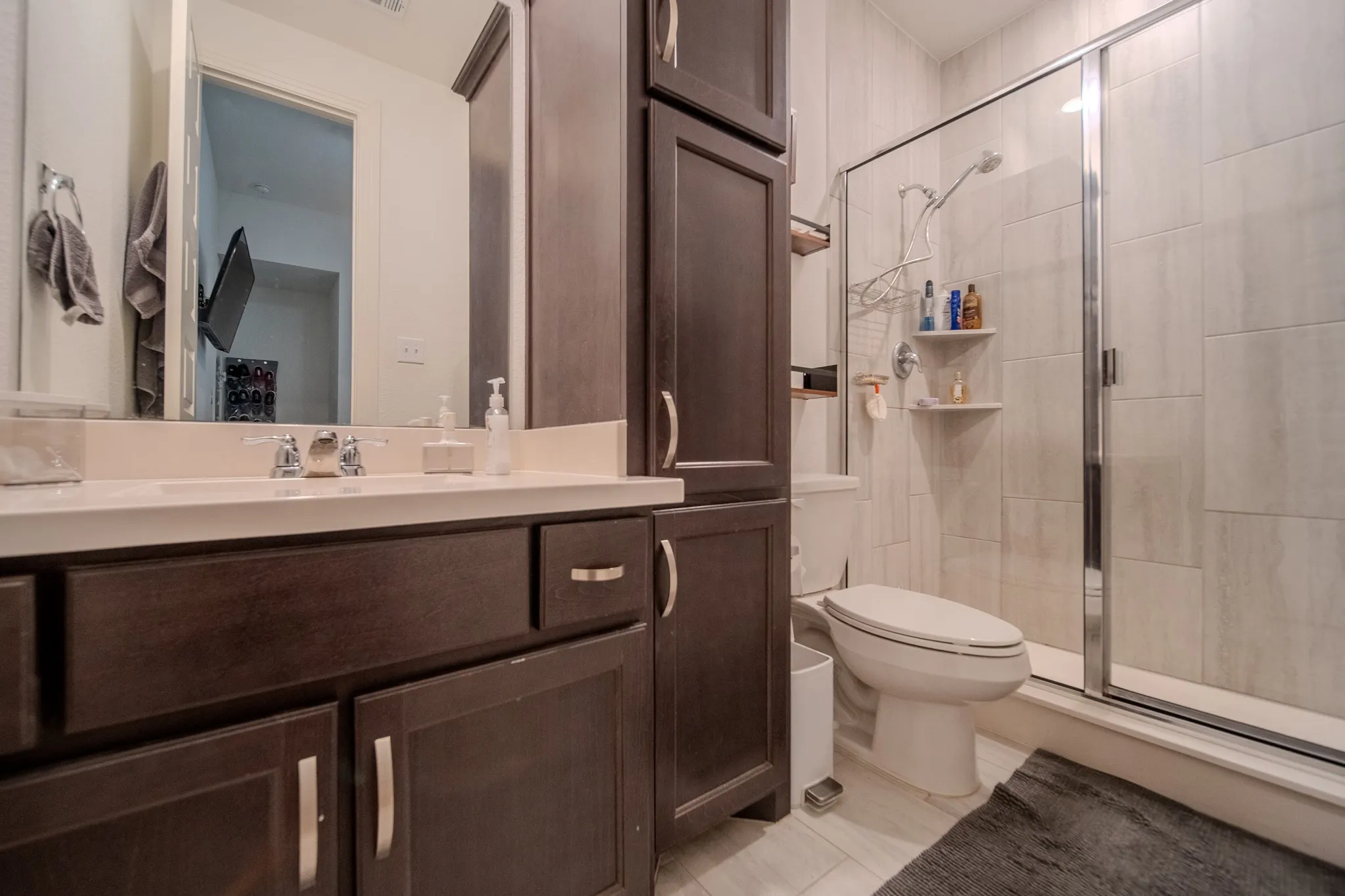 Wood-finish cabinetry, built-in storage, and a glass-enclosed shower