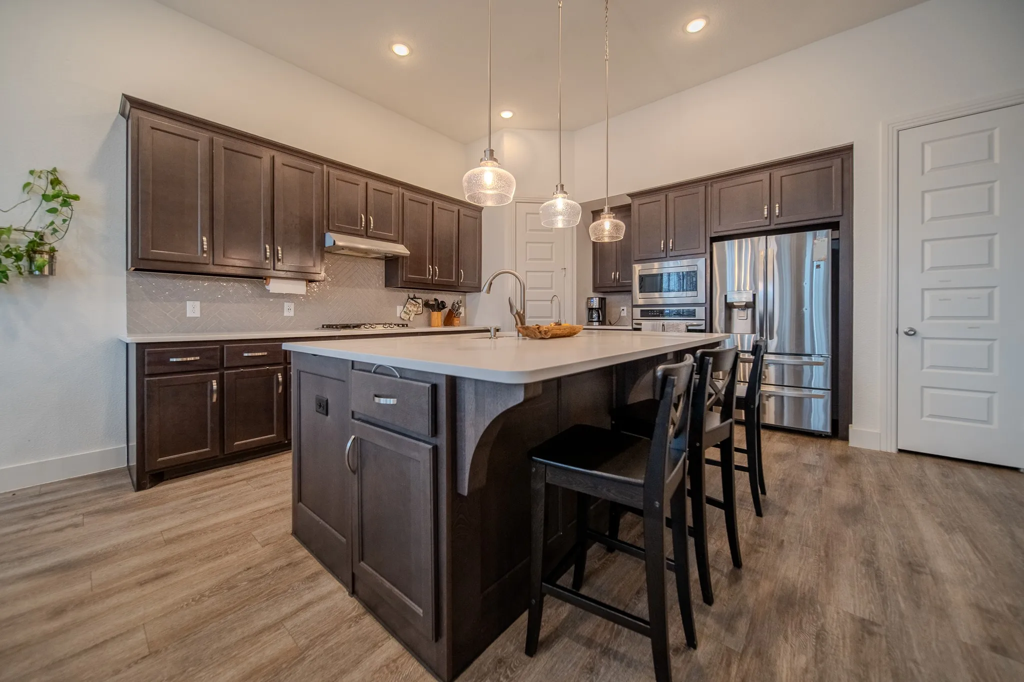 Kitchen featuring dark wood-finish cabinetry, stainless steel appliances, a light-toned countertop, and wood-finish flooring