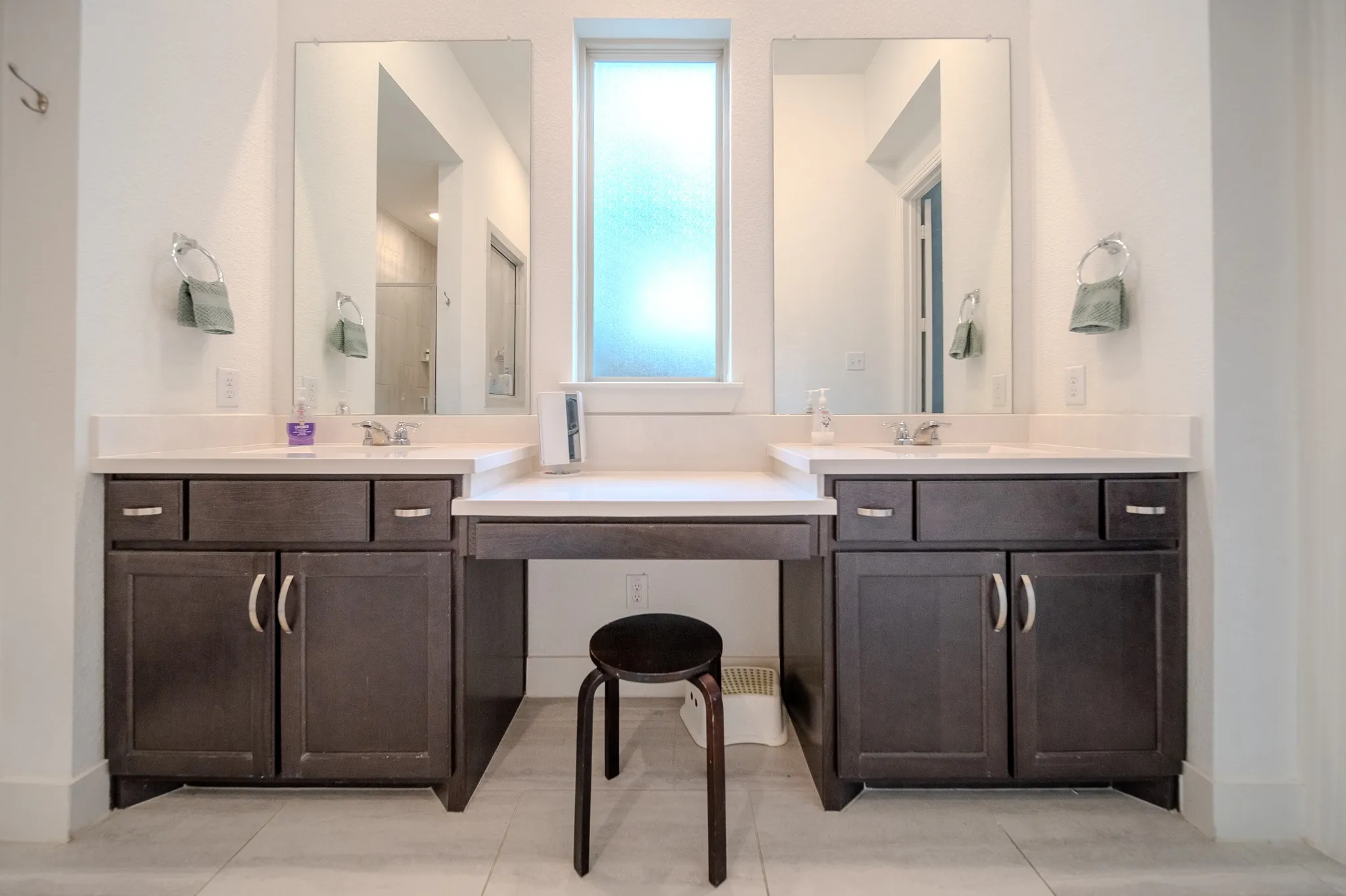 Dual dark wood-finish vanities with undermount sinks, light-toned countertops, and frameless mirrors