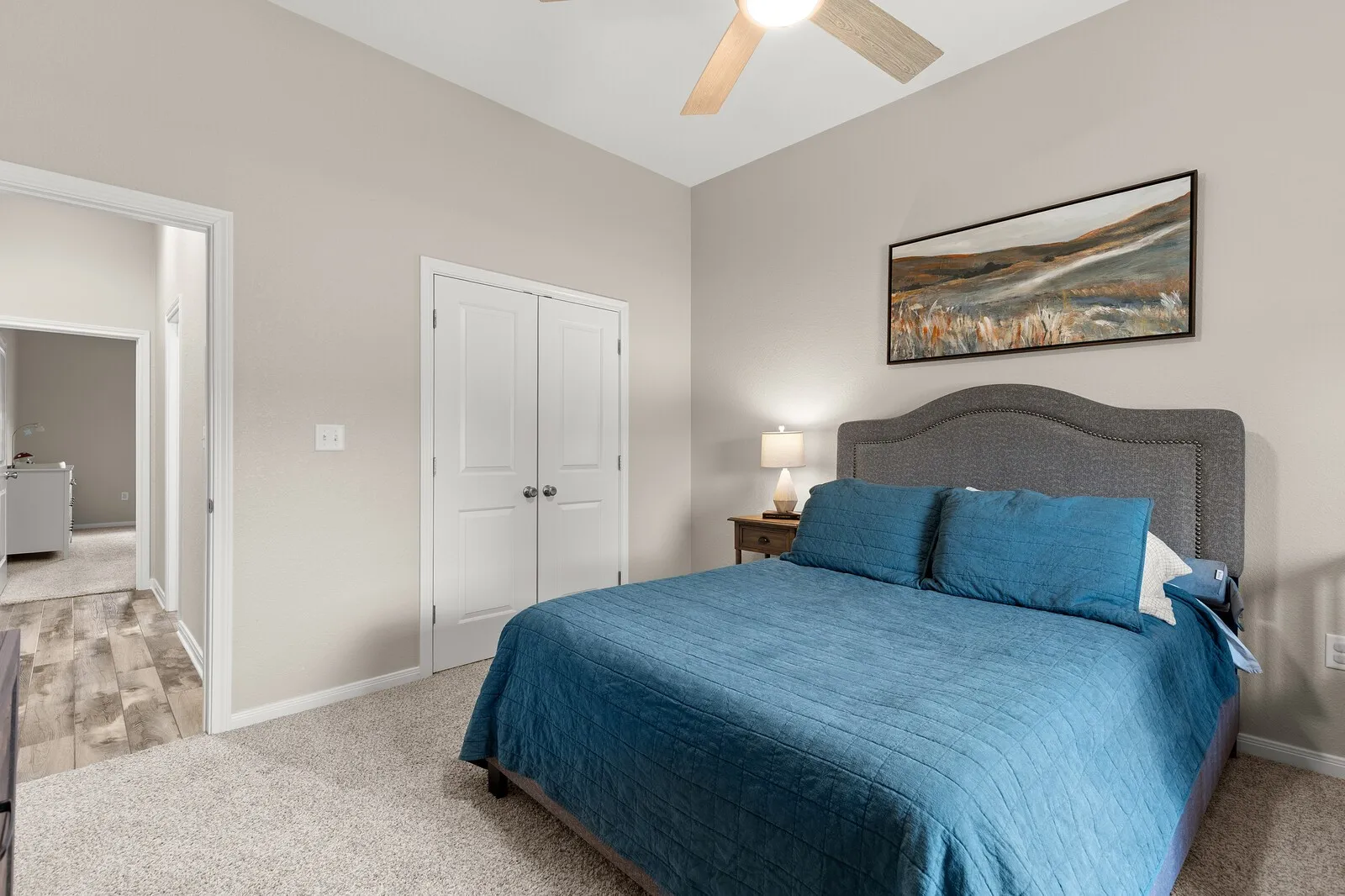 Vaulted ceiling with a ceiling fan, plush carpet, neutral wall tones, and double closet doors