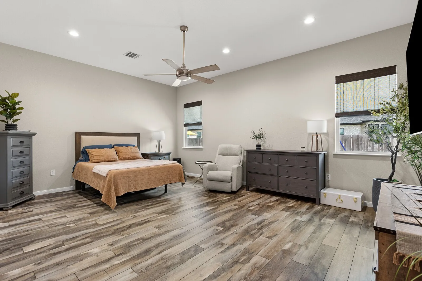 Spacious room featuring wood-finish flooring, high ceilings with recessed lighting, and a ceiling fan