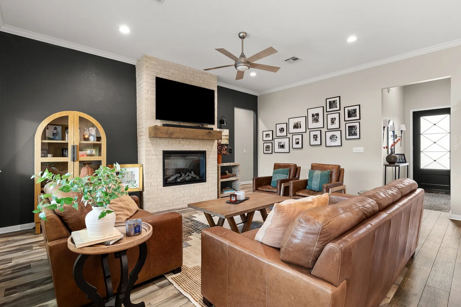 Living area featuring a brick-surround fireplace with a wood mantel, wood-finish flooring, recessed lighting, and a ceiling fan
